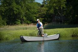 Inflatable TC16 Travel Canoe by Backcountry Sportsman floating on water with paddles, showcasing its compact, durable design.