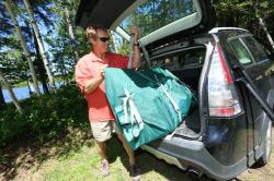 Backcountry Sportsman TC16 Travel Canoe inflated with three people, showing its compact design and bright orange color.