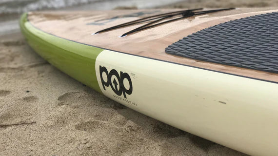 Backcountry Sportsman 12'0 Americana paddle board with a woman standing on it in a lake setting, showcasing its size and design.