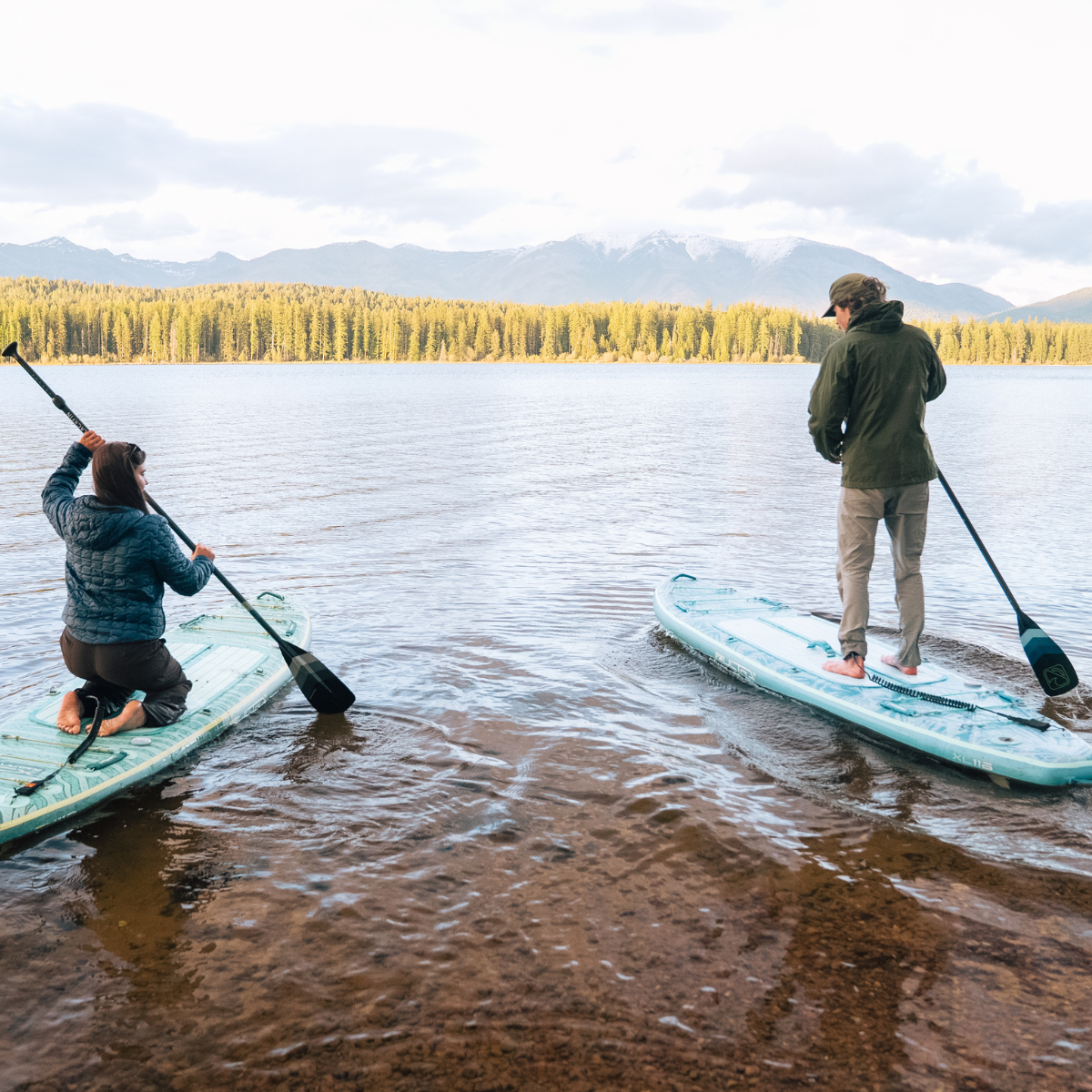 iROCKER US XL ULTRA™ 3.0 paddle board lying on water with a paddle and carrying bag for all-around water adventures.