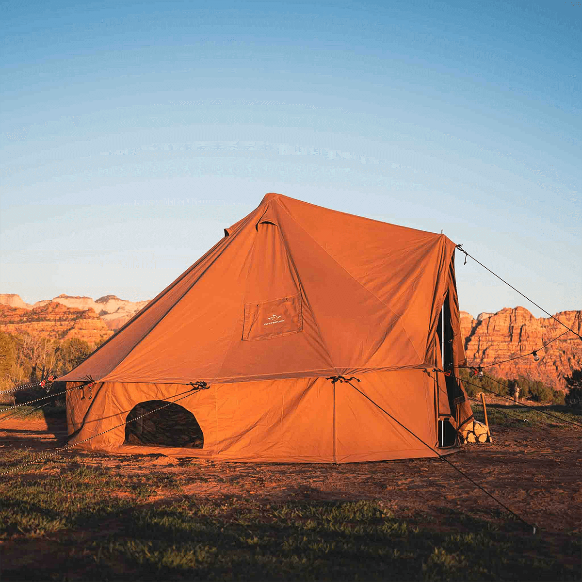 Desert red 13-foot Regatta Bell Tent by White Duck Outdoors shown from the side with sunlight illuminating the fabric.