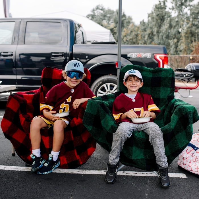 Red plaid City Bonfires Chair Blanket draped over a chair, showcasing its cozy, warm fabric and classic pattern for outdoor comfort.