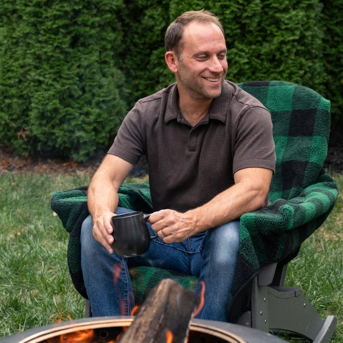 Green plaid City Bonfires Chair Blanket draped over a chair, showcasing its cozy, soft fabric and stylish pattern.