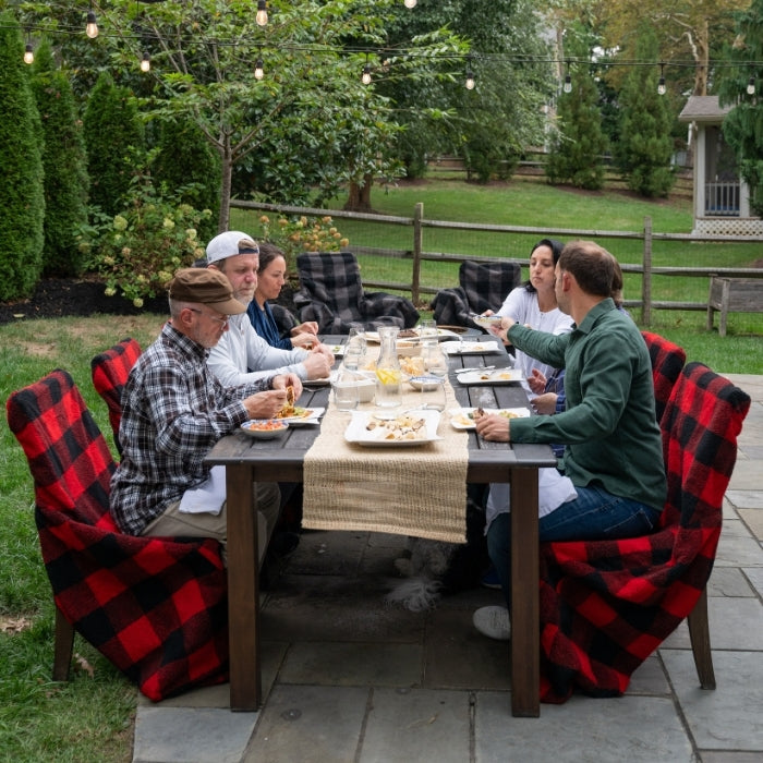 Red plaid City Bonfires Chair Blanket draped over a chair, showcasing its cozy, warm fabric and classic pattern.