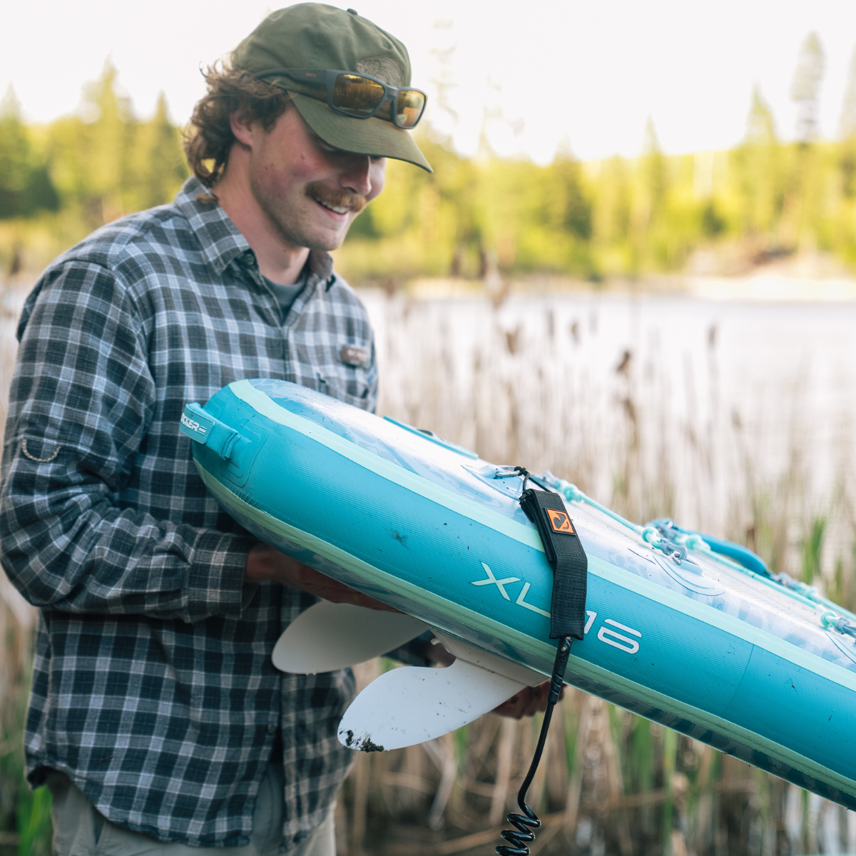 iROCKER US XL ULTRA™ 3.0 paddle board lying on a beach with a carrying handle and textured deck for stability.