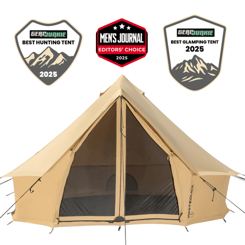 White Duck Outdoors 13-foot Regatta Bell Tent set up outdoors with its canvas fabric and conical shape, showcasing its spacious design.