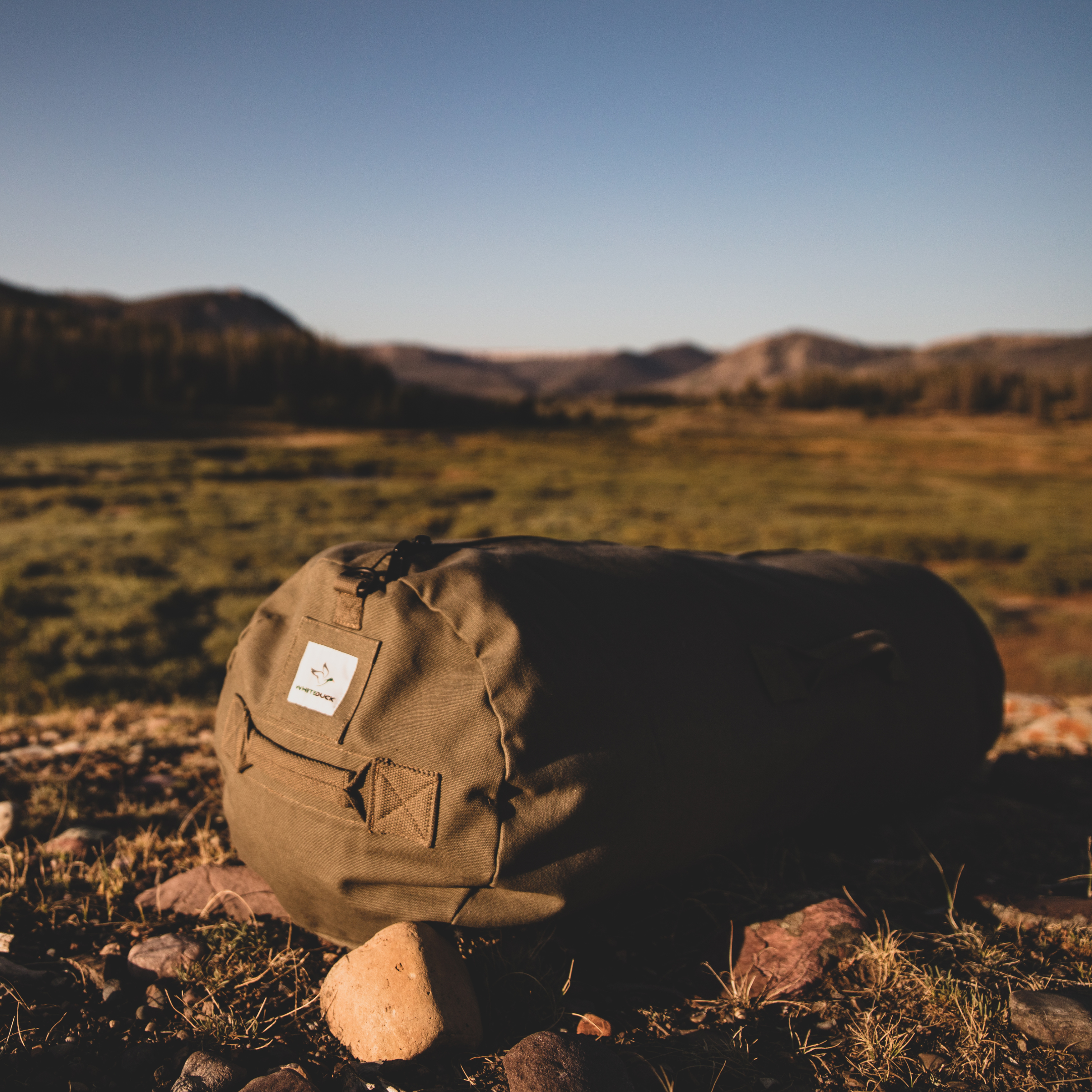 White Duck Outdoors Hoplite Canvas Duffel Bag showing durable beige canvas material and sturdy handles for travel and everyday use.