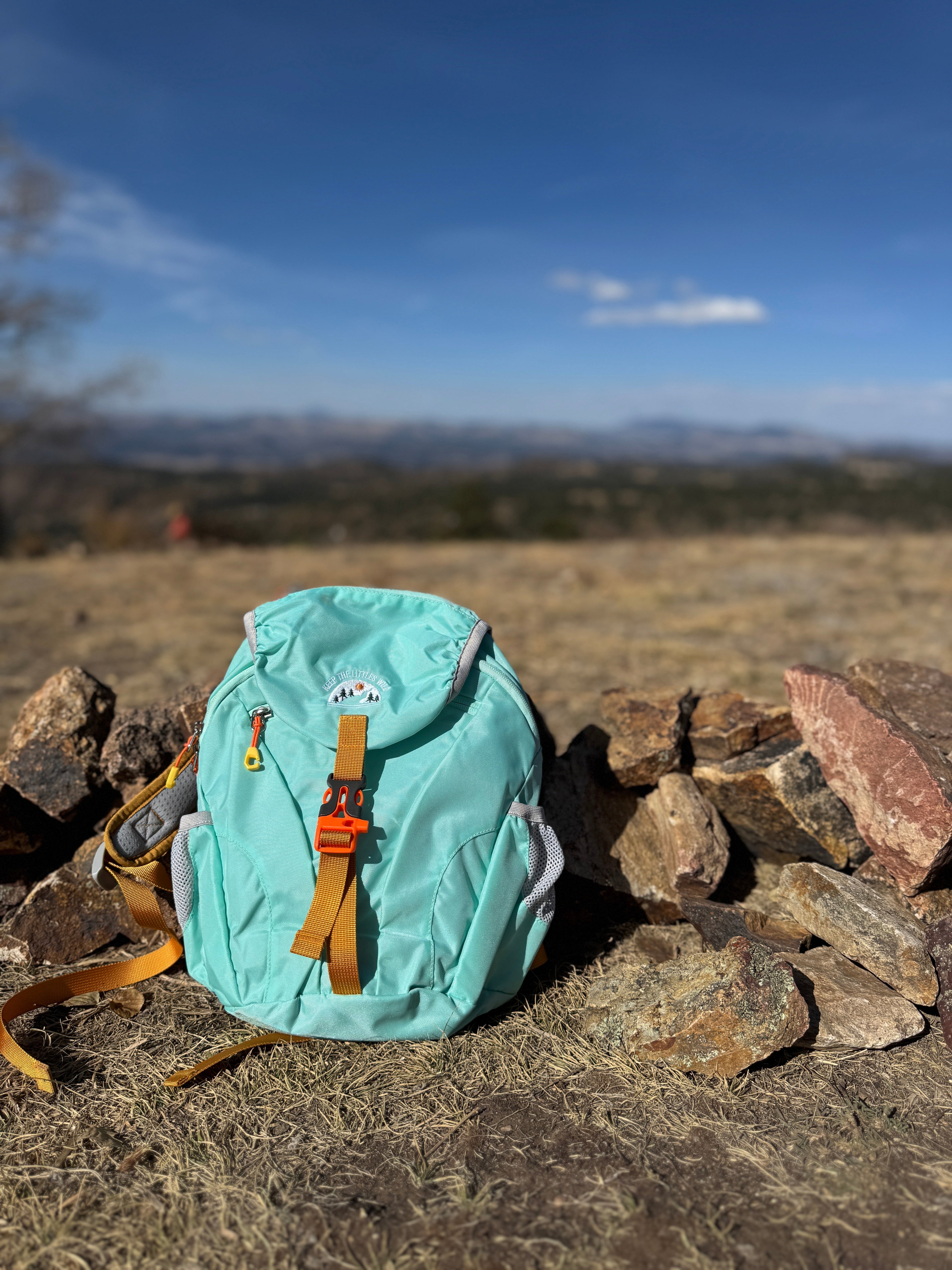 Light blue kids' hiking pack by Keep the Littles Wild with water bladder system, suitable for ages 2 to 7, showing adjustable straps and compartments.