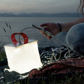 Alpenglow PackLite Max 2-in-1 Power Lantern in outdoor setting, illuminating surrounding area with bright light.