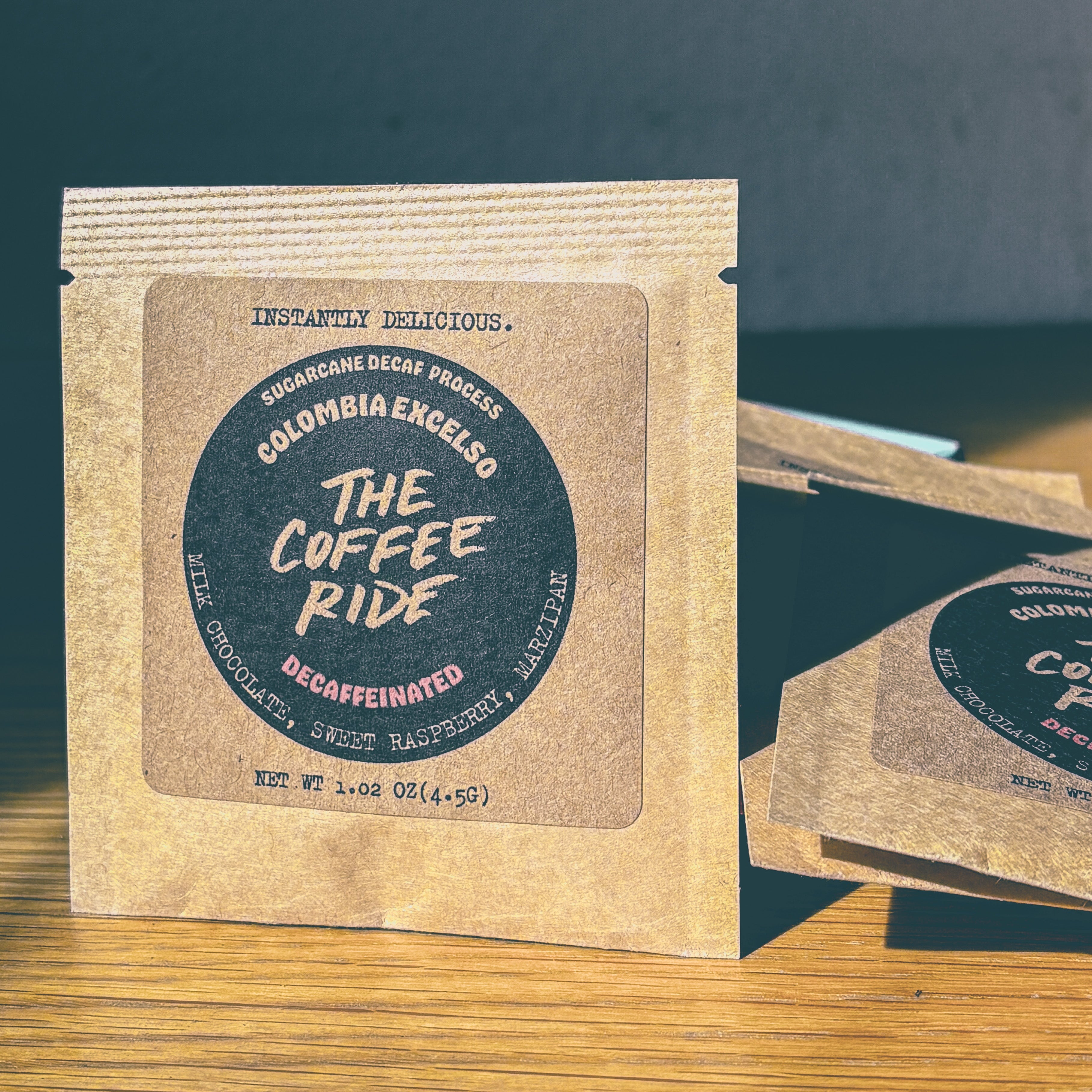 Decaf Colombia coffee from The Coffee Ride Coffee Roasting Co. in a bag with label, ready for brewing.