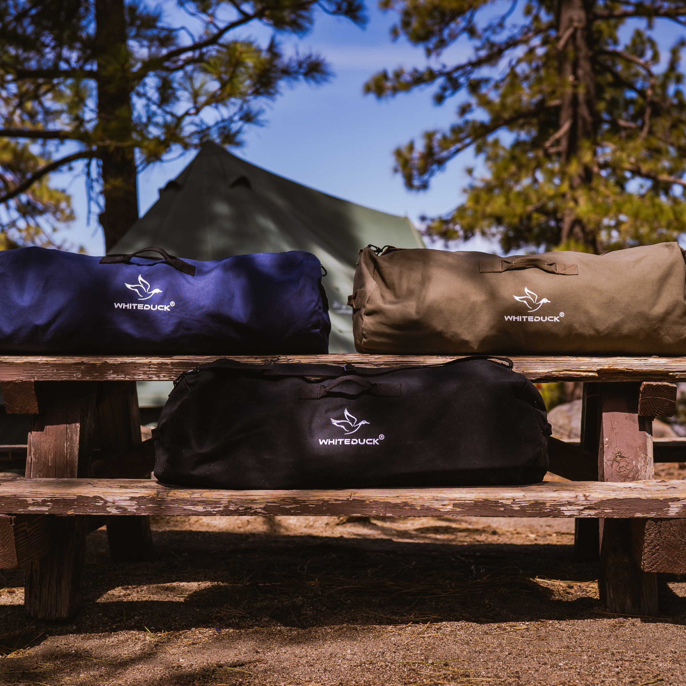 White Duck Outdoors Hoplite Canvas Duffel Bag showing a durable beige bag with black handles and zipper closure.