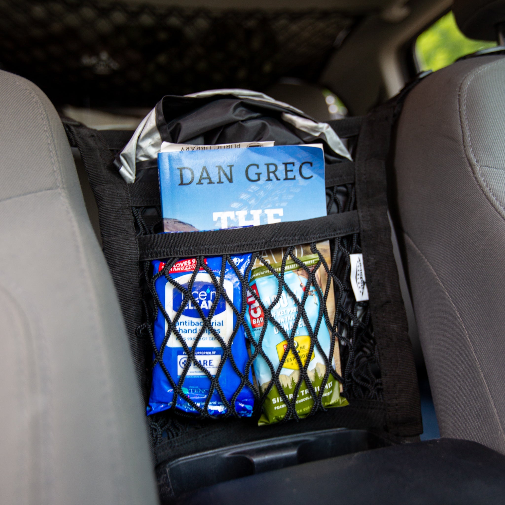 Universal seat divider storage net by Flatirons Overland, showing a flexible mesh organizer for vehicle seat separation.