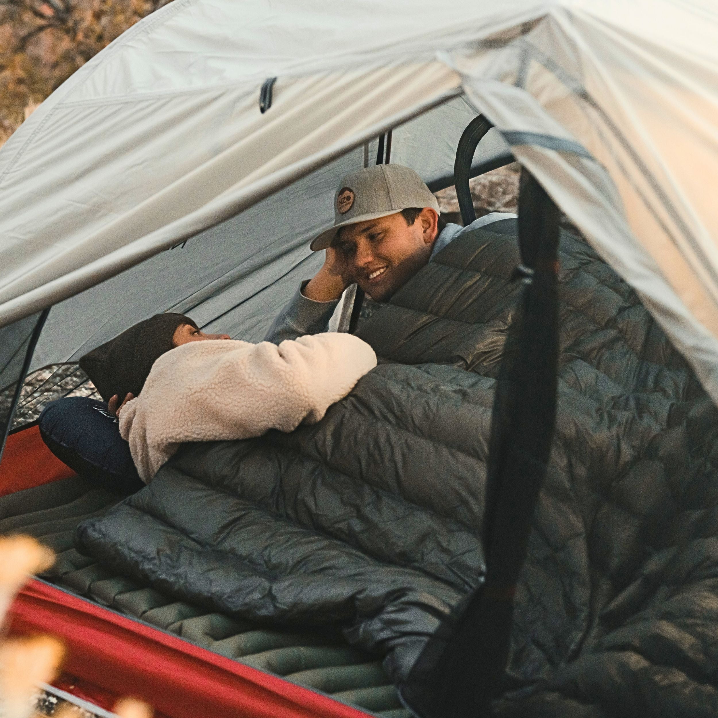 Near Zero Outdoor Gear QUILT ONE Sleeping Bag in vibrant colors, displayed fully open on a grassy outdoor surface.