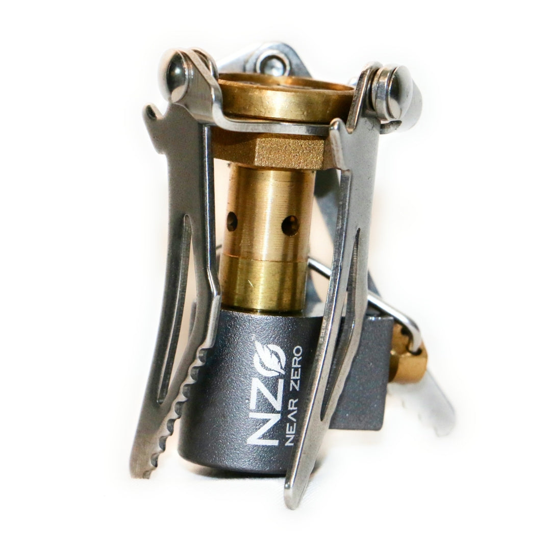 Near Zero Outdoor Gear mini stove accessory shown on a table with camping gear, compact and lightweight for outdoor cooking.