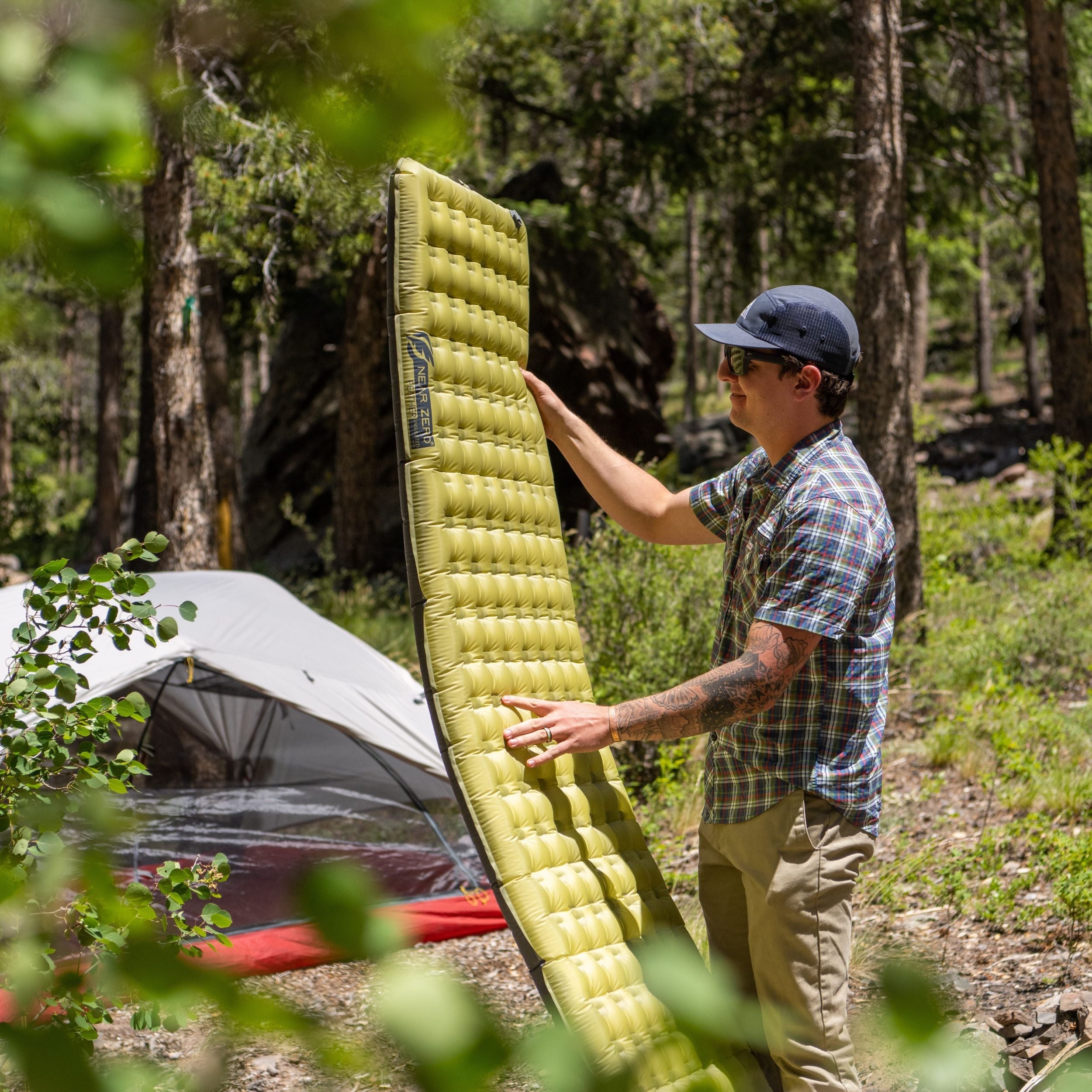 Near Zero Outdoor Gear insulated inflatable sleeping pad spread out, showing its foam and air-filled structure for camping comfort.