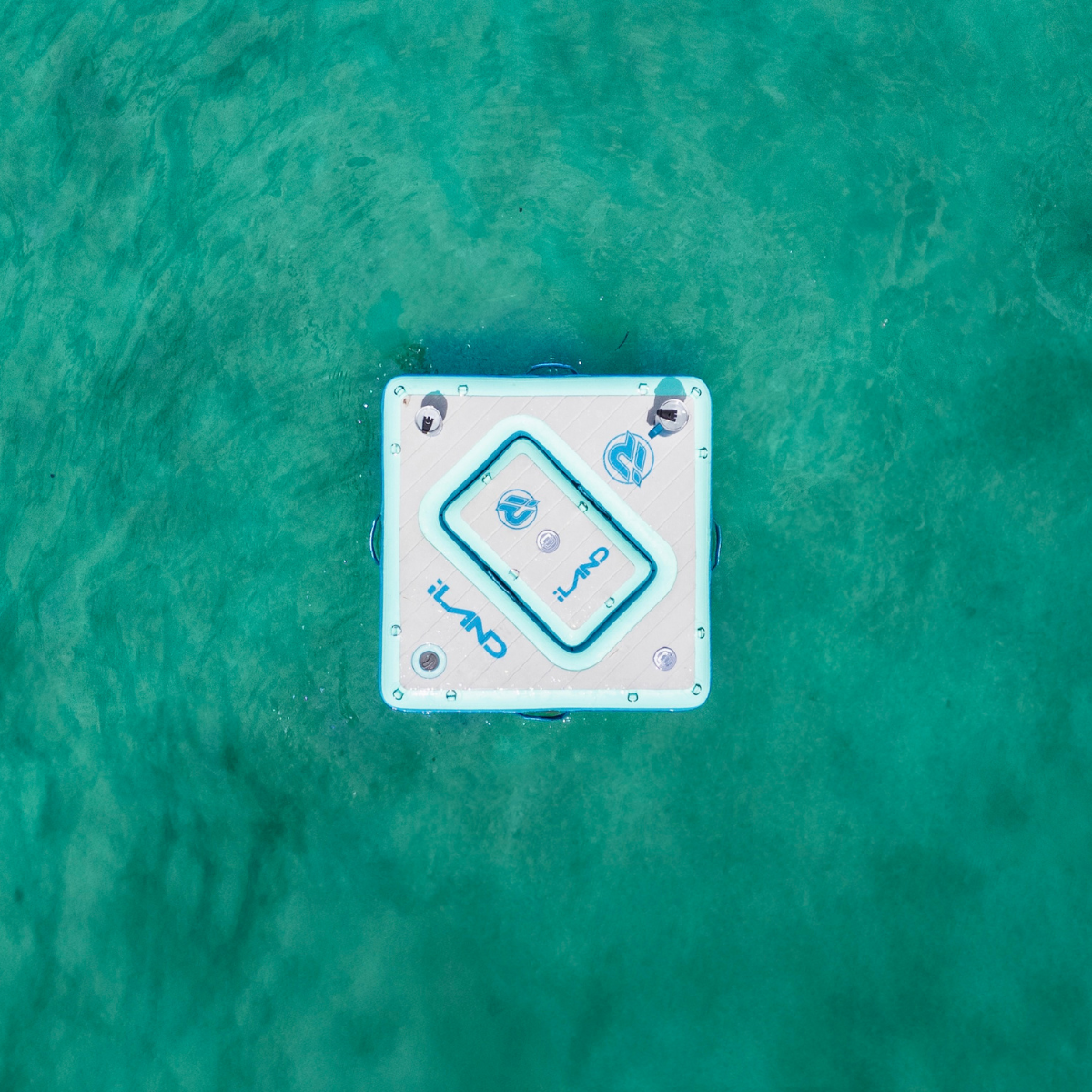 iROCKER US inflatable floating bar with multiple drink holders and seating area on bright blue water during daytime.