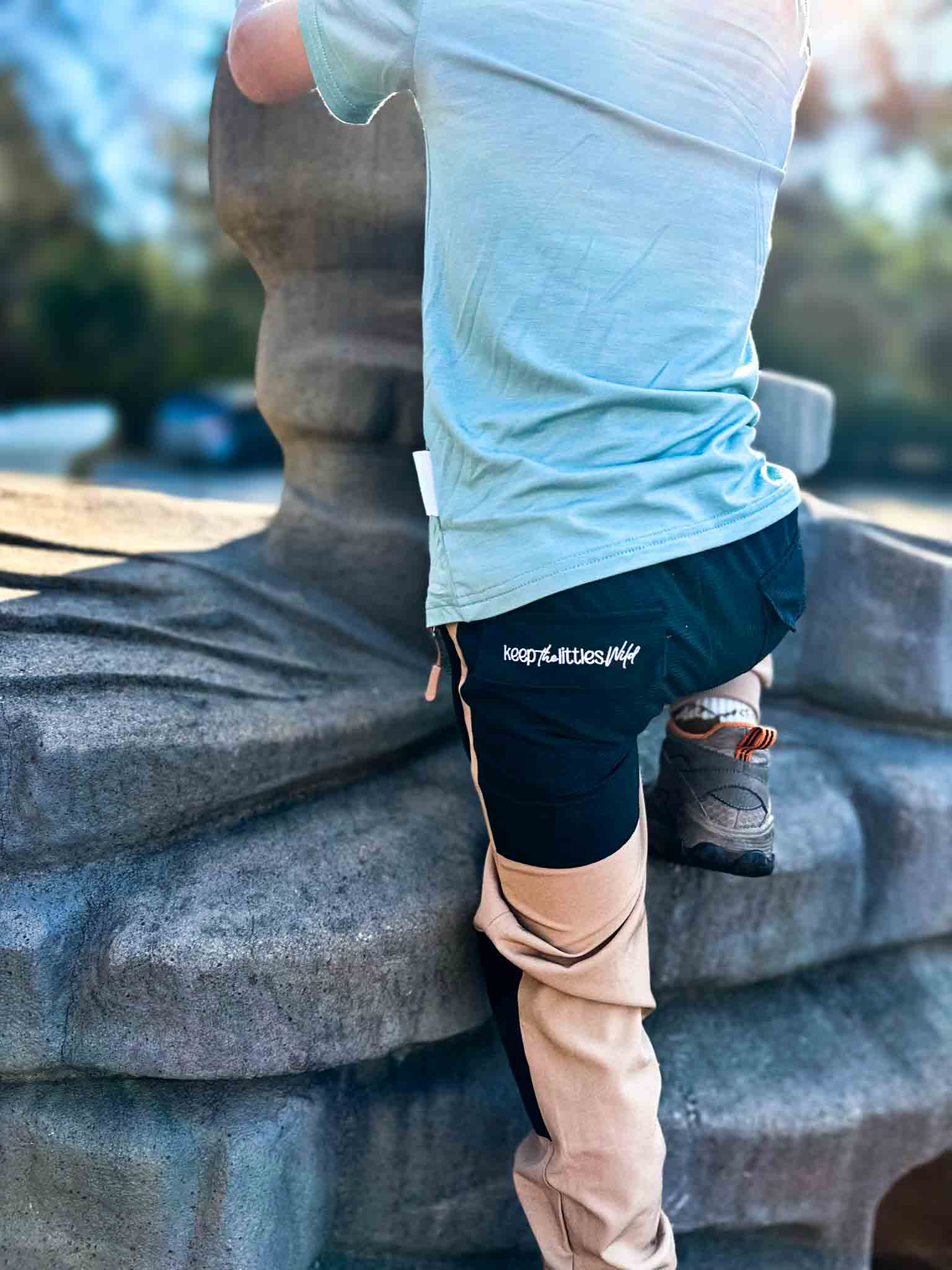 Water-resistant tan hiking pants by Keep the Littles Wild, shown with a focus on durable outdoor fabric and adjustable waistband.