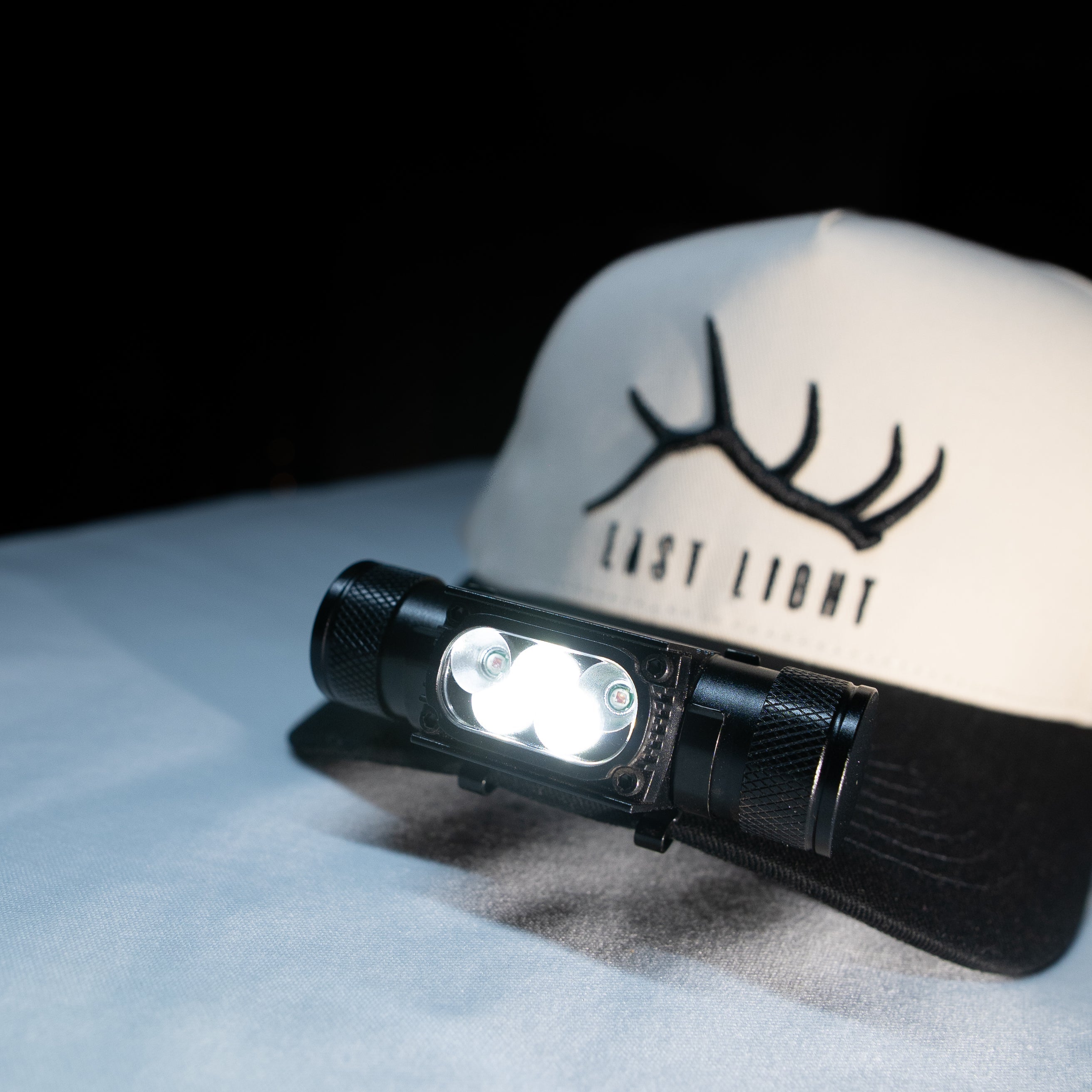 Last Light LLC headlamp hat clip attached to a backpack, featuring a compact lighting device for hands-free illumination.