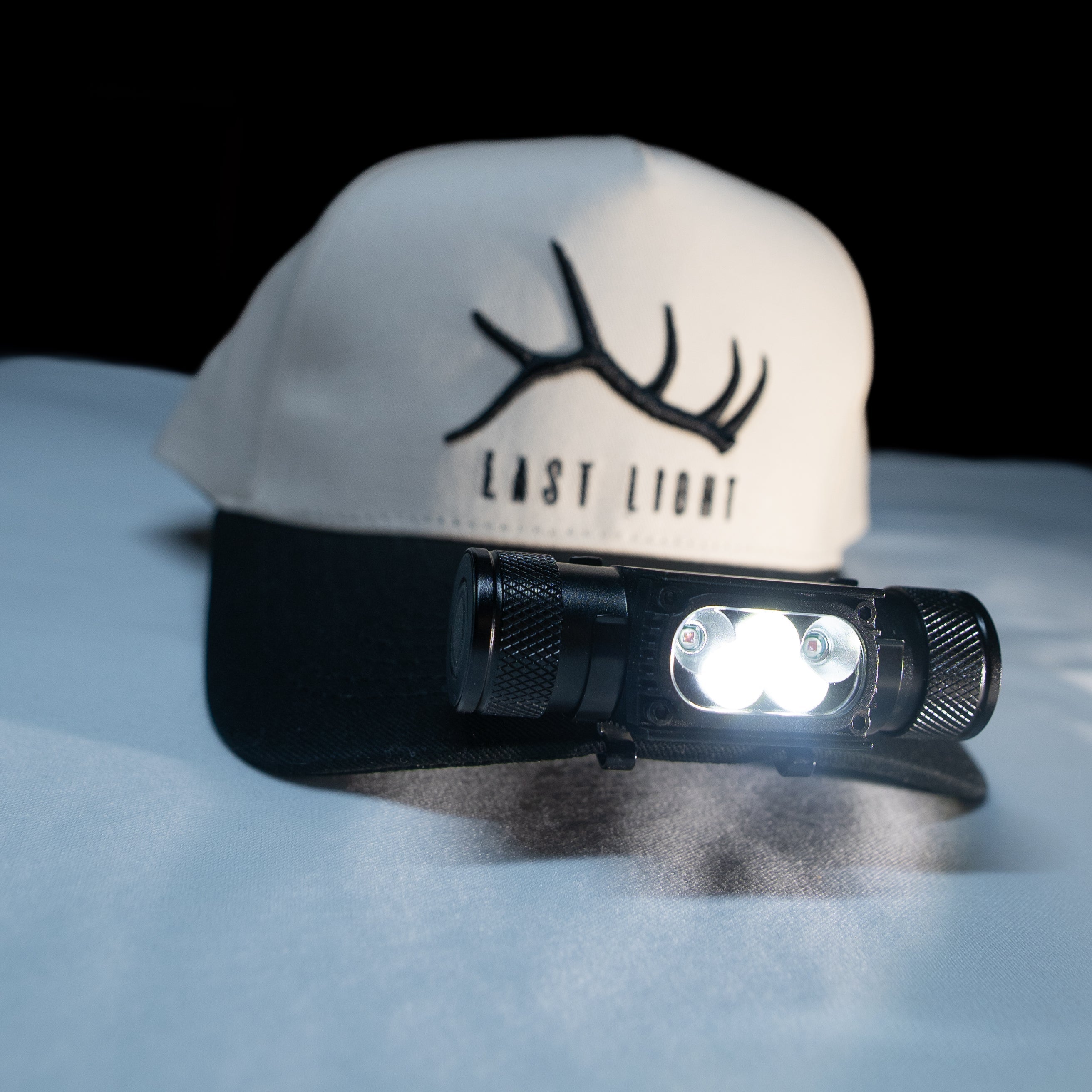 Last Light LLC headlamp hat clip attached to a backpack, providing hands-free lighting for outdoor activities.