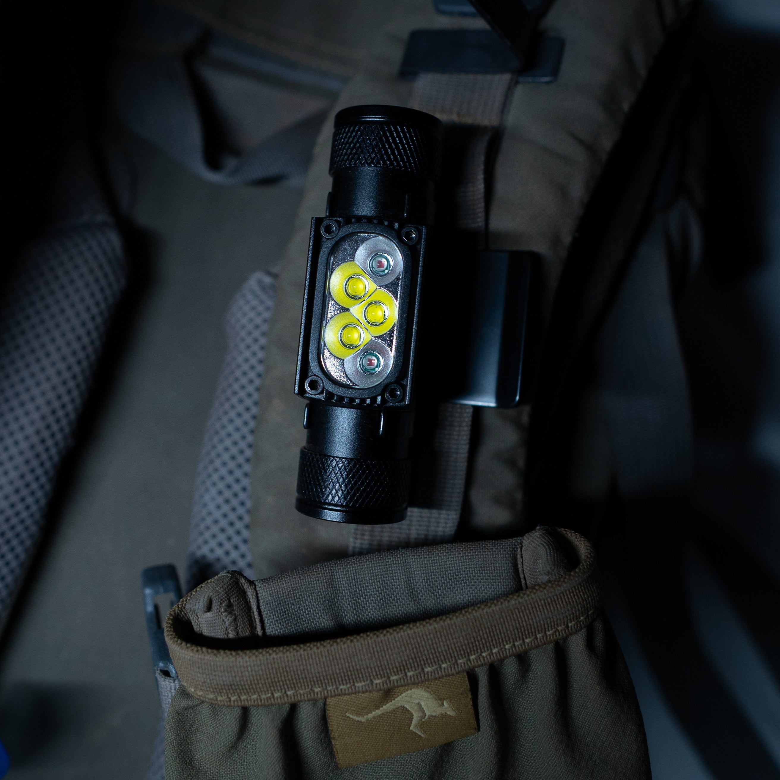 Last Light LLC headlamp hat clip attached to a backpack, providing hands-free lighting for outdoor activities.