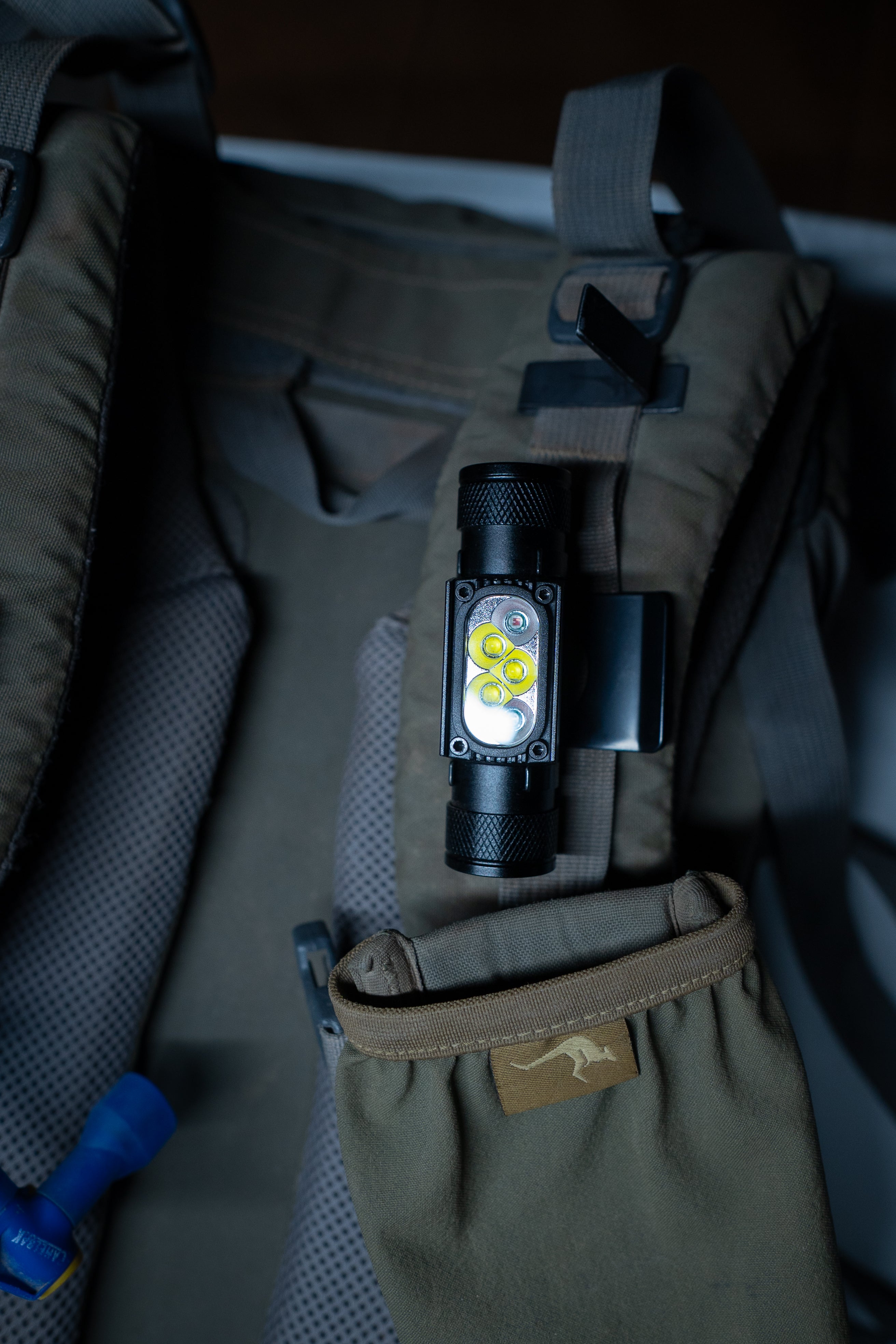 Last Light LLC headlamp hat clip attached to a backpack, providing hands-free lighting for outdoor activities.