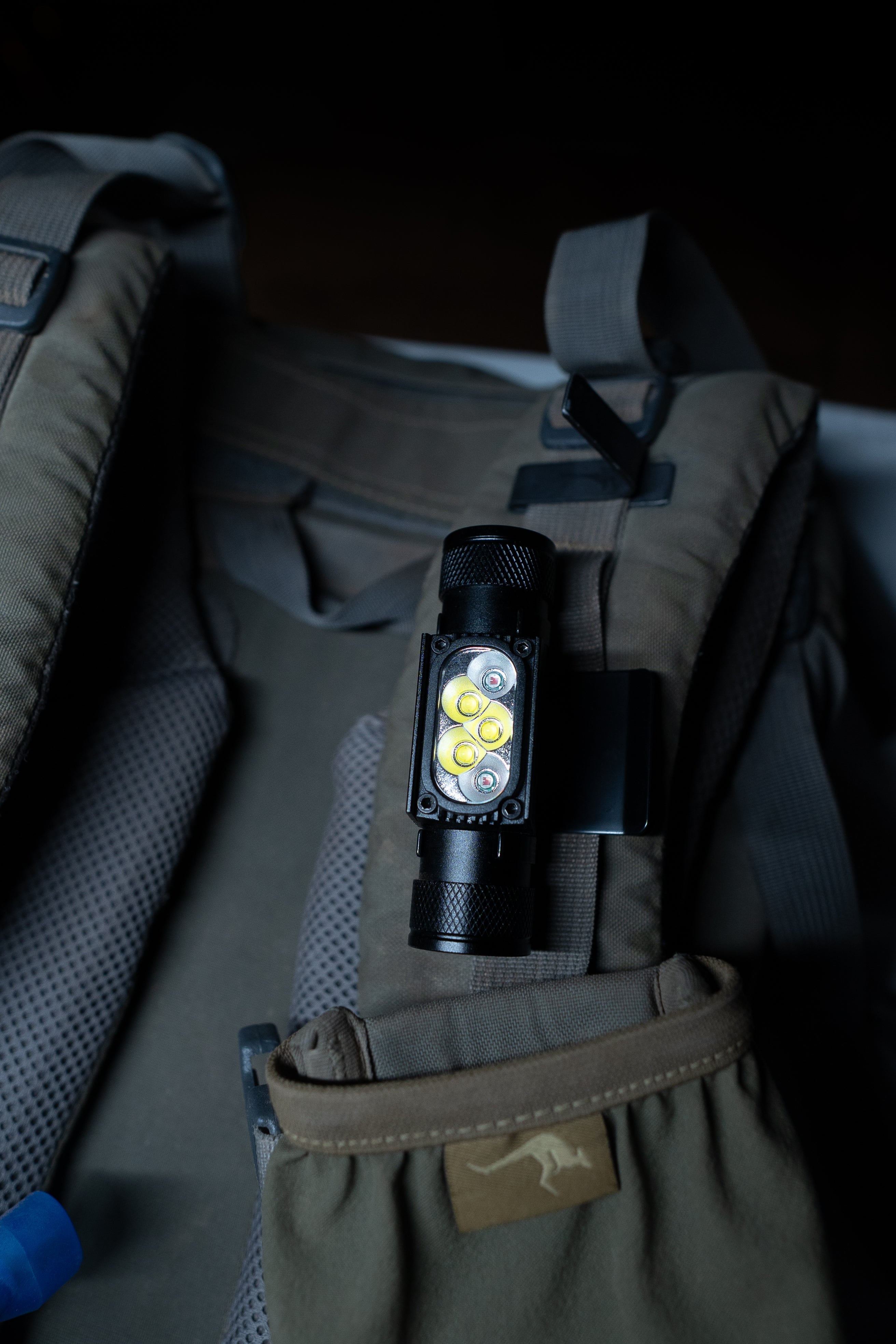 Last Light LLC headlamp hat clip attached to a backpack, providing hands-free lighting for outdoor activities.