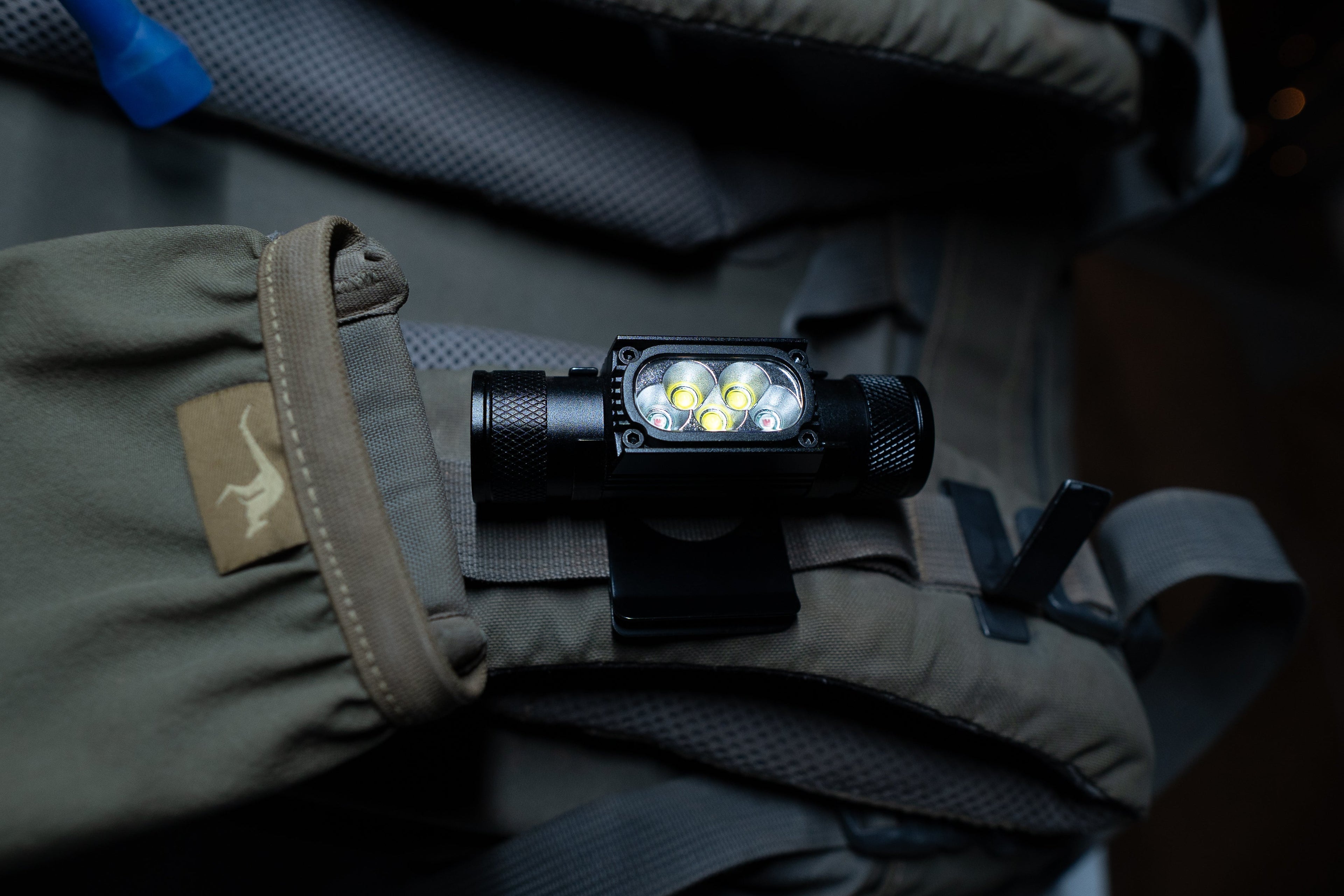 Last Light LLC headlamp hat clip attached to a backpack, providing hands-free lighting for outdoor activities.