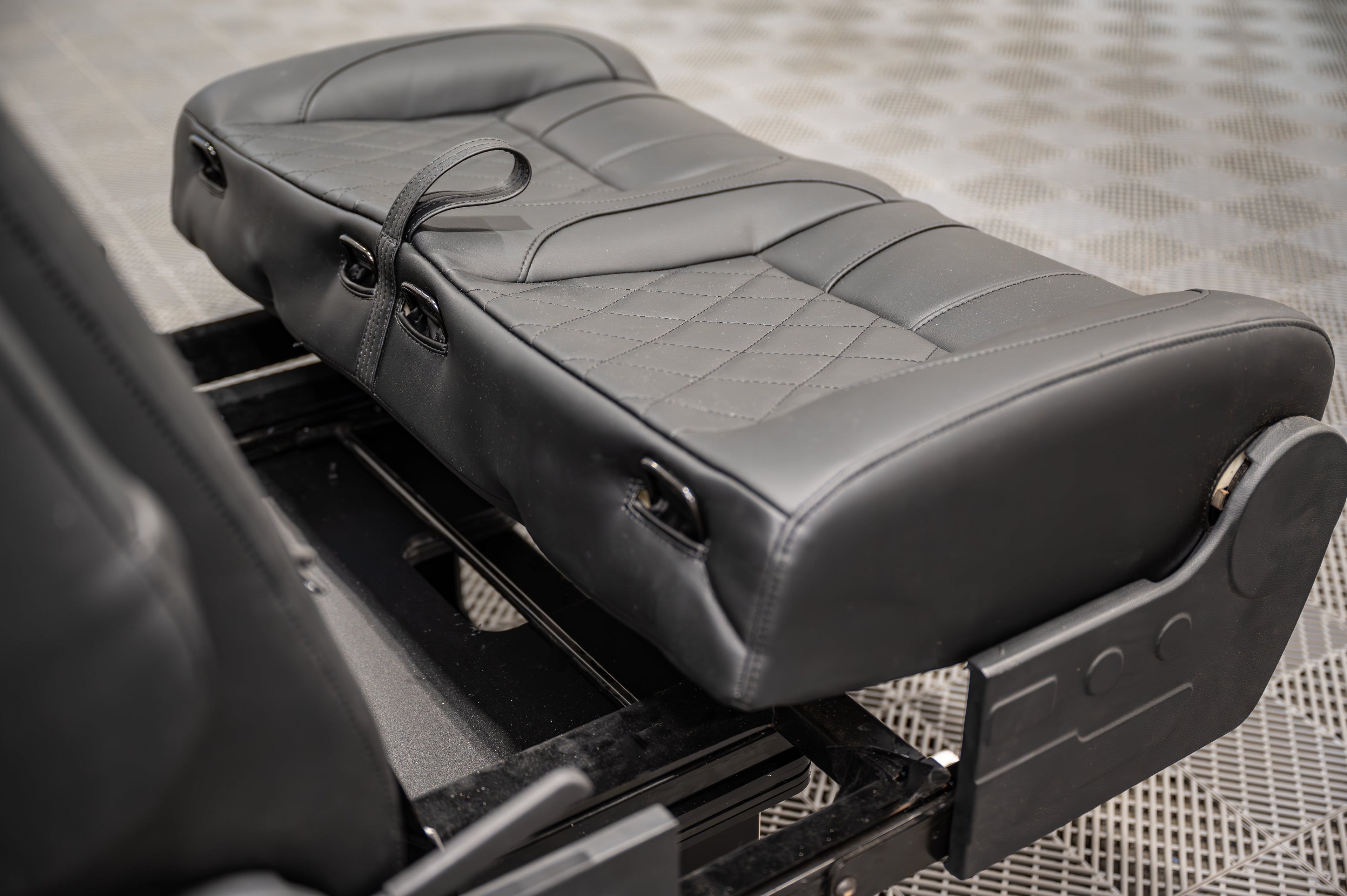 Alpine Van Works dual fold double bench-to-bed seat showing its seating and bed conversion features in a vehicle interior.