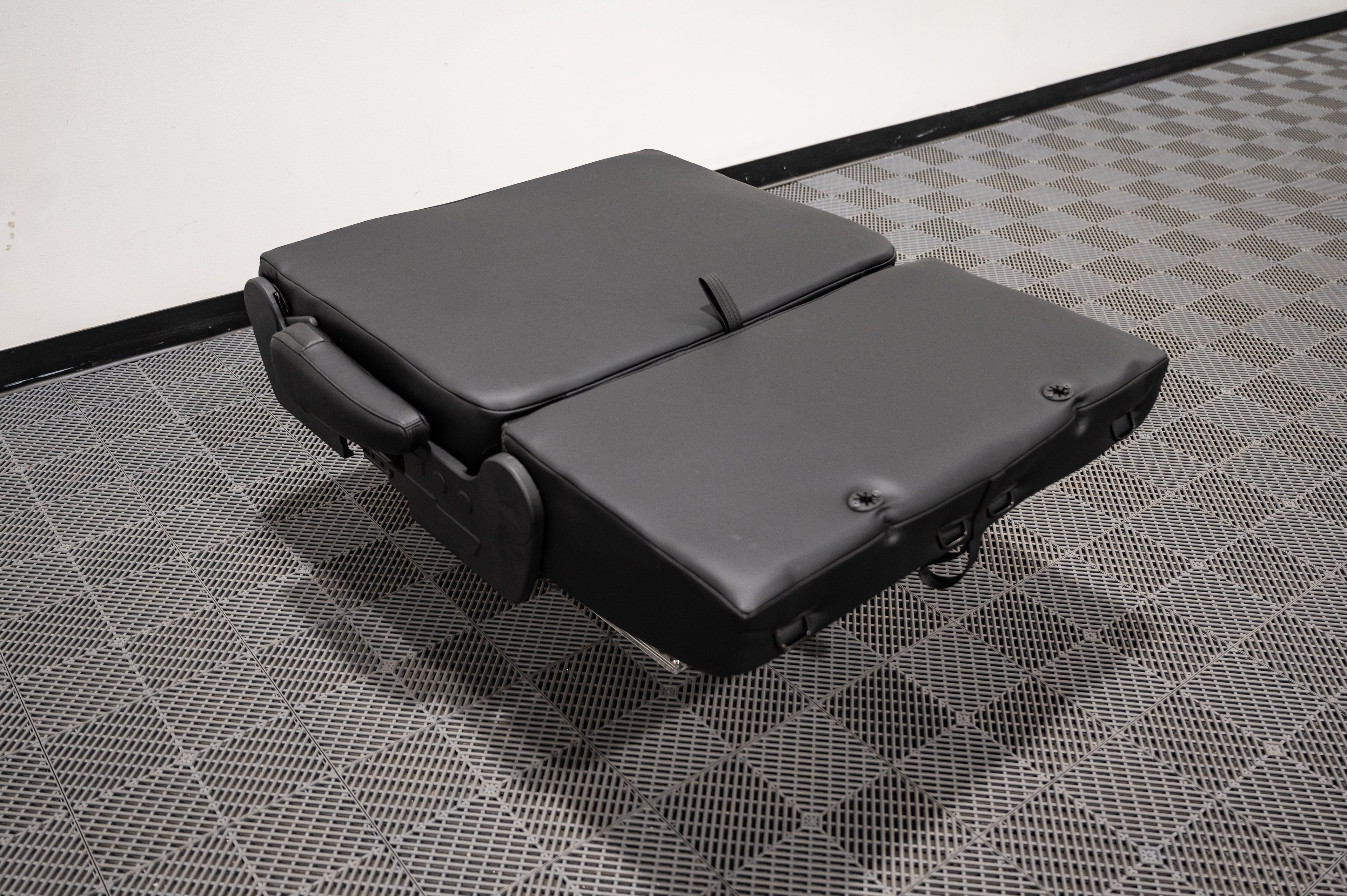 Alpine Van Works dual fold double bench-to-bed seat showing a versatile seating and sleeping solution with cushioned surfaces.