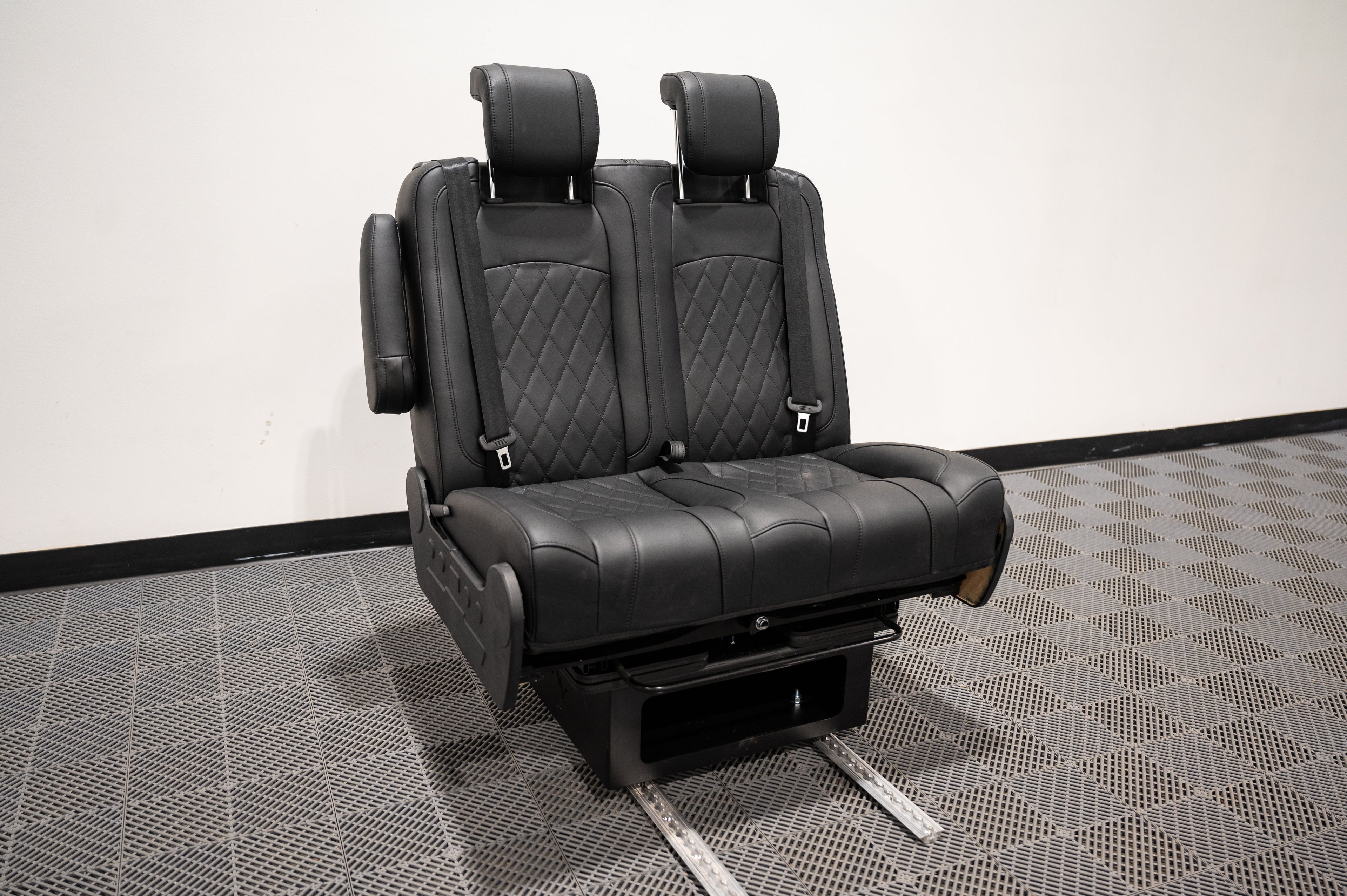 Alpine Van Works dual fold double bench-to-bed seat with upholstered cushions and sturdy metal frame, designed for versatile seating and sleeping.