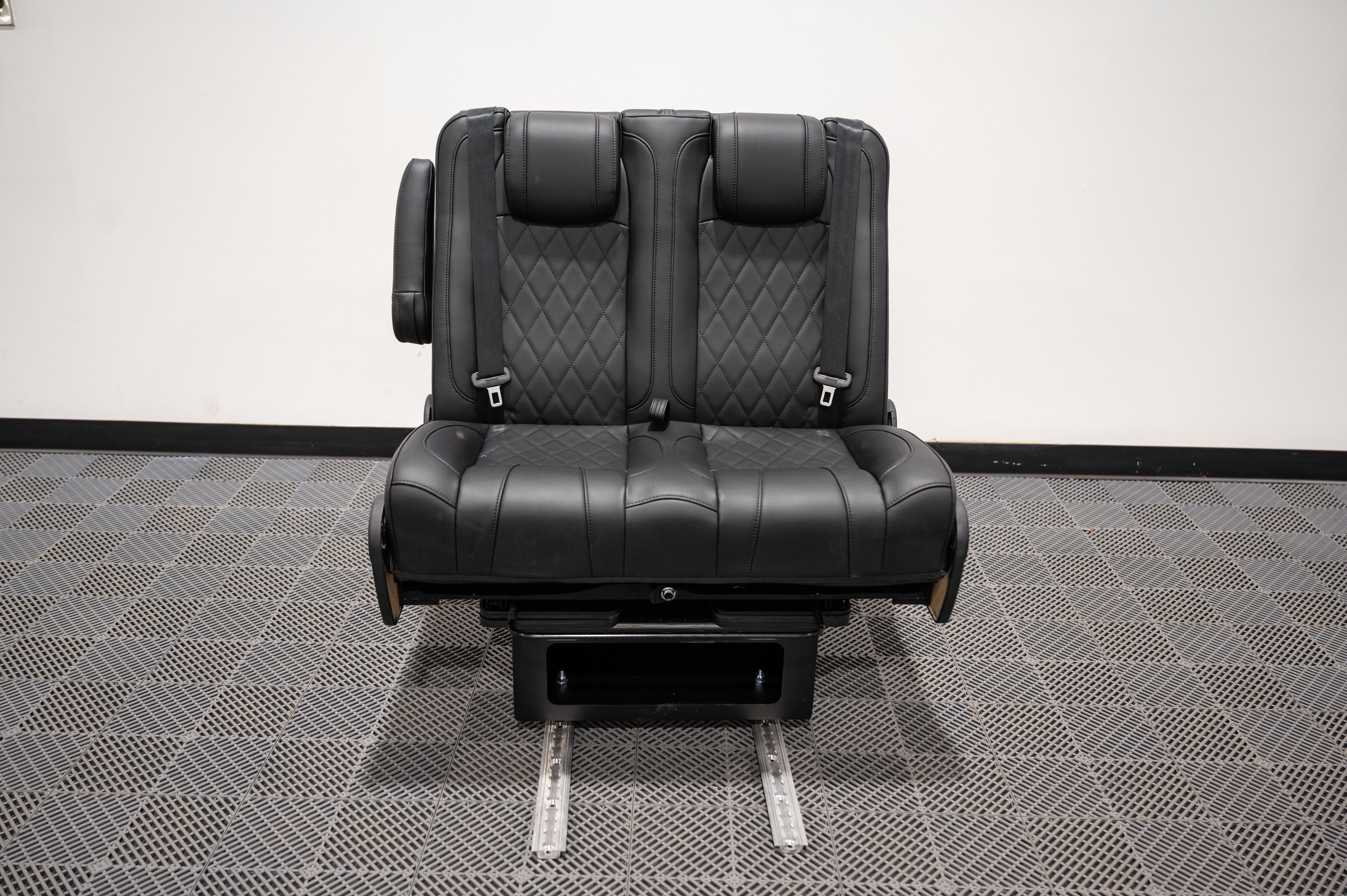 Dual fold double bench-to-bed seat by Alpine Van Works, LLC, showing the versatile seating and sleeping conversion in a vehicle interior.