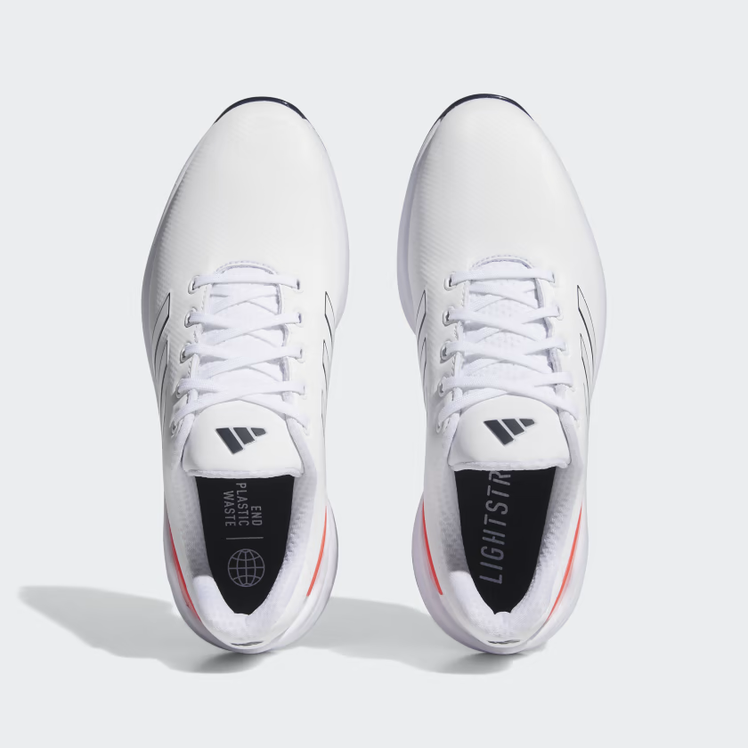 Adidas Men's ZG23 golf shoes in black with white accents, featuring breathable mesh and grip sole for golf course performance.