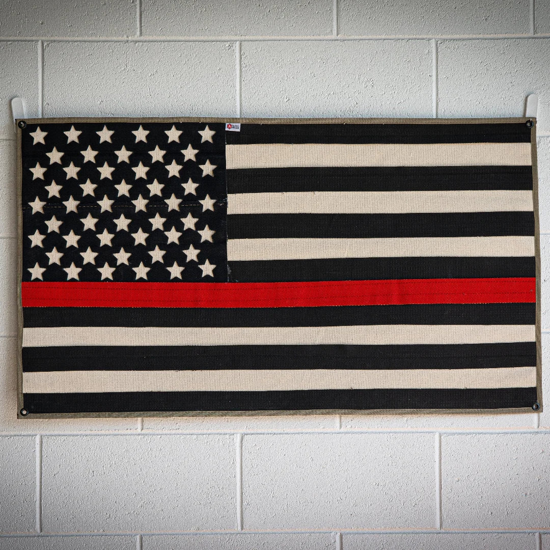 American flag made from recycled fire hose with a thin red line, symbolizing firefighting pride, on a white background.