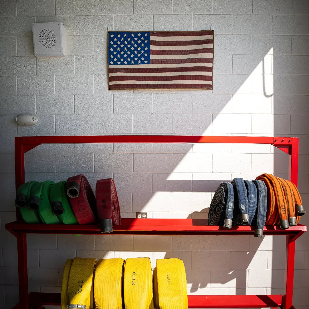 Vintage American flag made from recycled fire hose by Recycled Firefighter, displaying bold red, white, and blue colors in a rugged design.