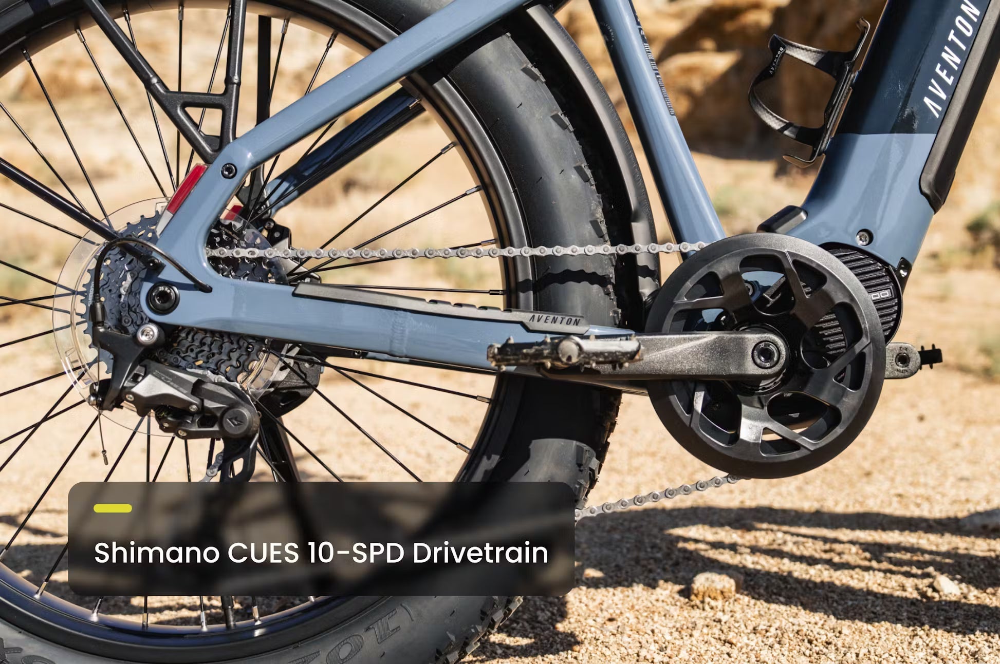 Rex E-Bikes Aventon Aventure.M E-Bike with black frame, front suspension, and 27.5-inch wheels, parked outdoors on a trail.