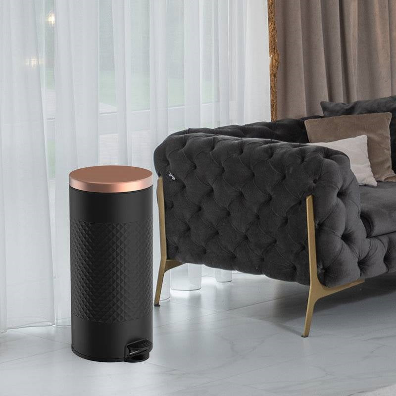 Black and gold metal hands-free 8-gallon step-on trash can in kitchen with sleek design and foot pedal for easy waste disposal.