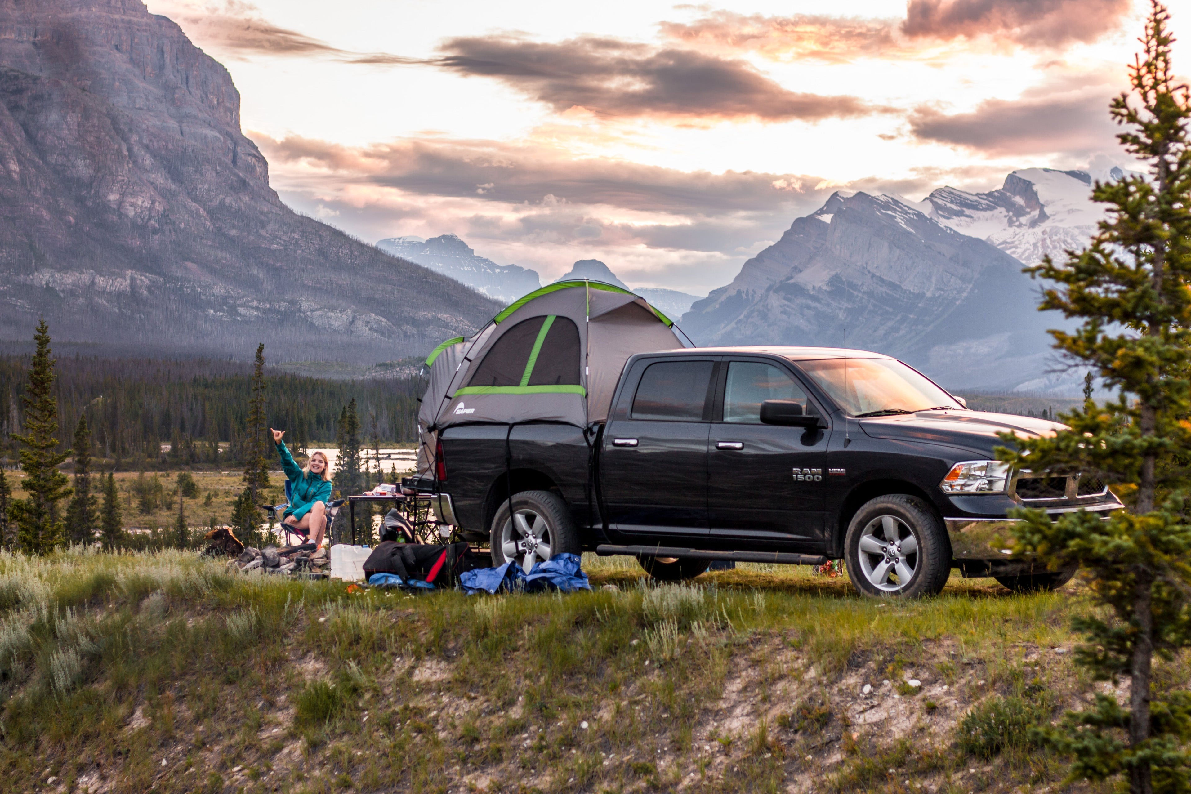 Backcountry Sportsman truck tent set up on a pickup truck in a forested camping area, showcasing outdoor adventure gear.