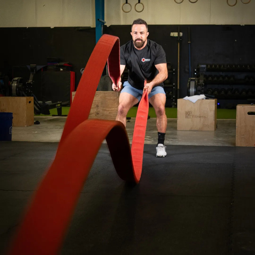 Recycled Firefighter 50FT Cadet Cord battle rope coiled on the floor, durable training equipment for strength and conditioning.