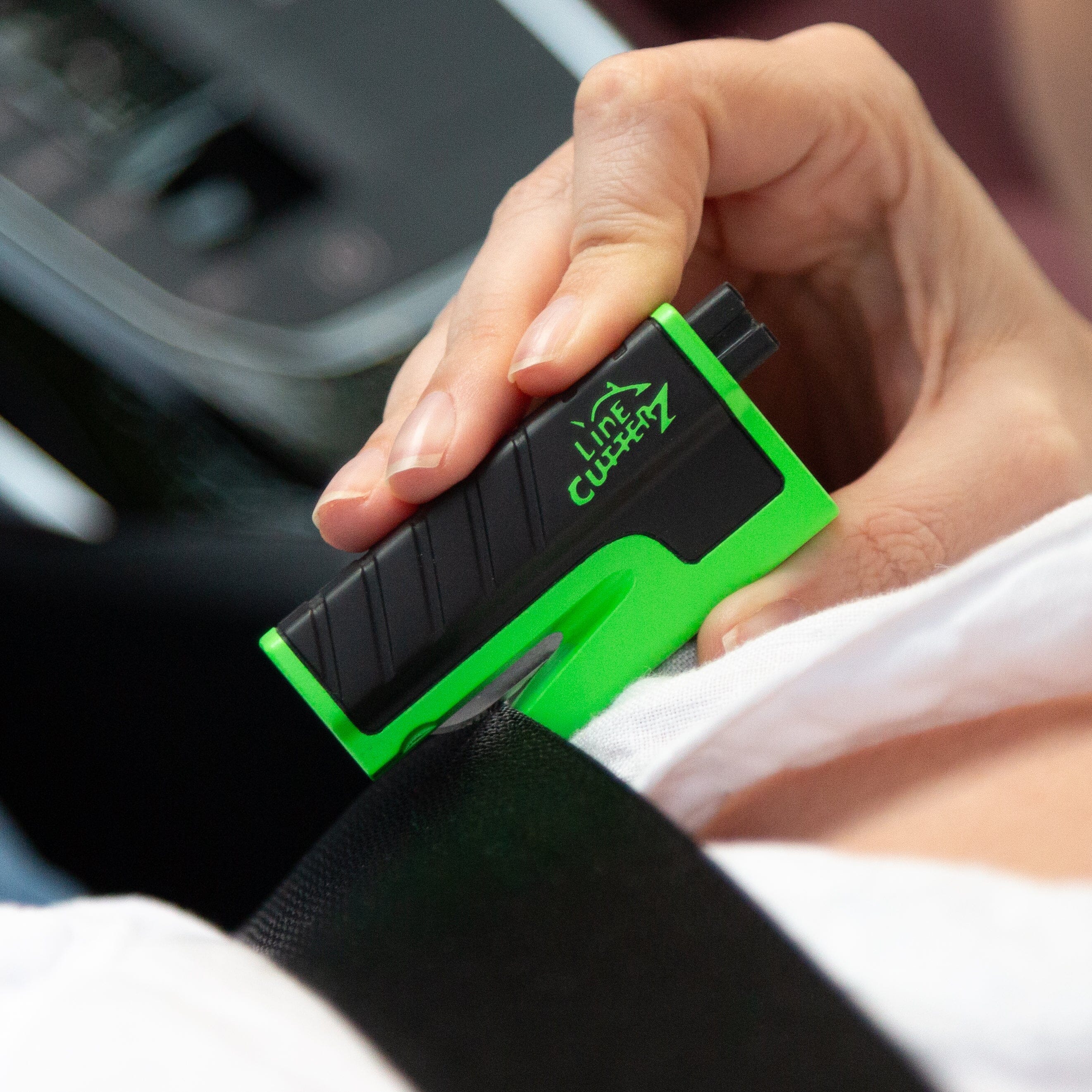 Line Cutterz VET vehicle escape tool cutting seatbelt in a lifestyle setting, showcasing its compact cutter design for emergency use.