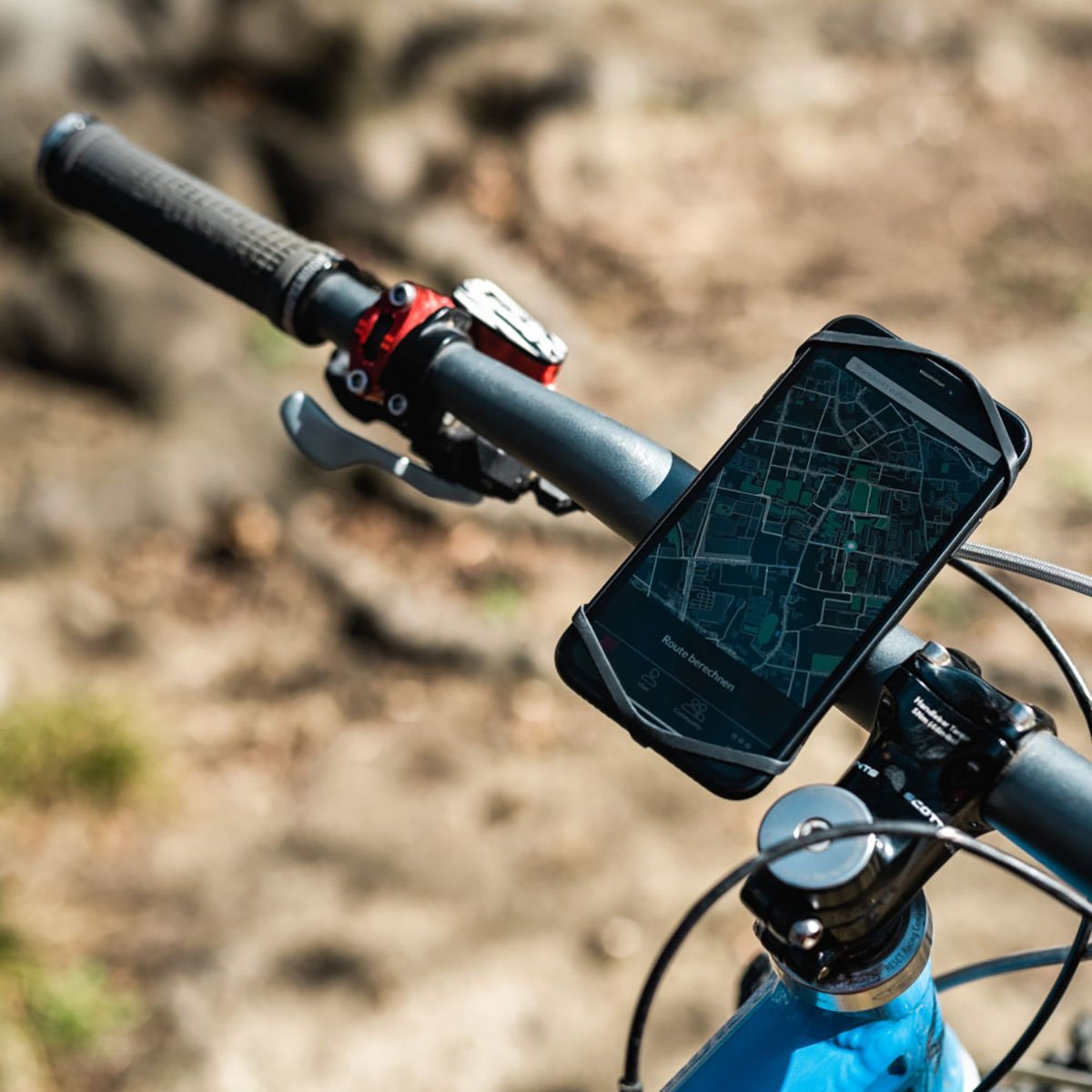 Red ZEITBIKE FINN universal bicycle phone mount attached to handlebars with a smartphone securely held in place.