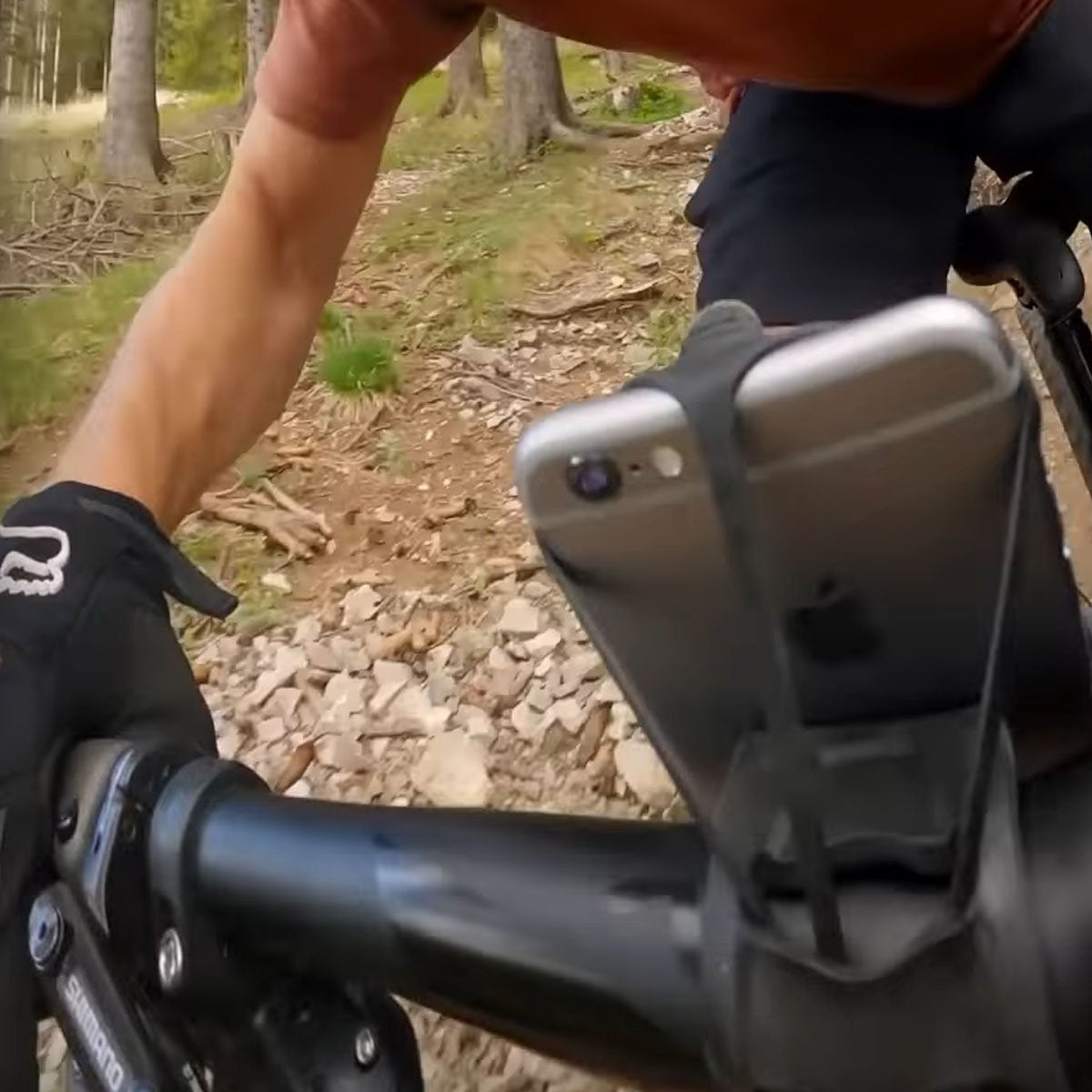 Red ZEITBIKE FINN universal bicycle phone mount attached to a bike handlebar, securely holding a smartphone during a ride.