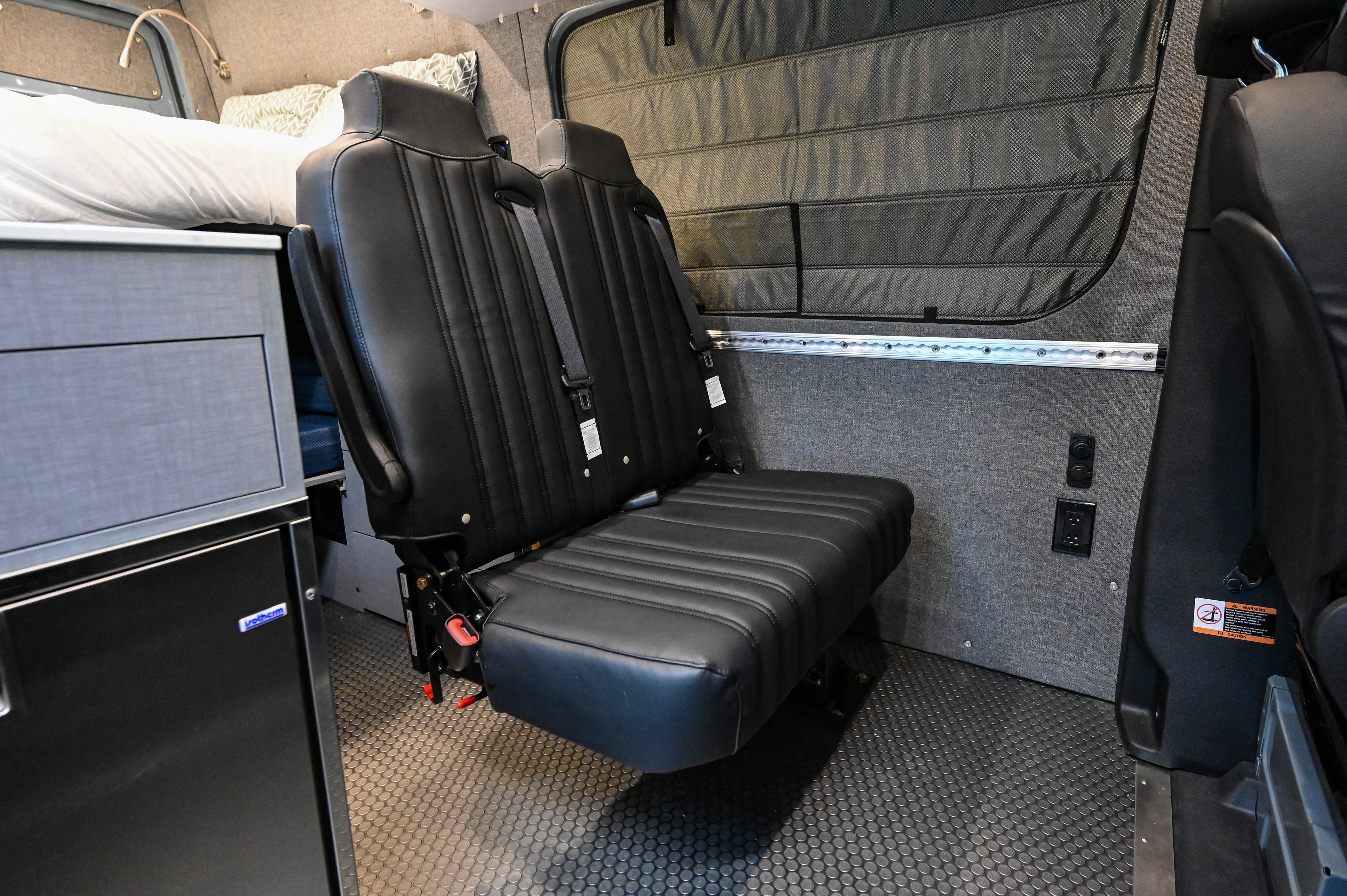 Alpine Van Works Hide N' Go Seat in a vehicle, compact foldable seating solution for versatile interior comfort.