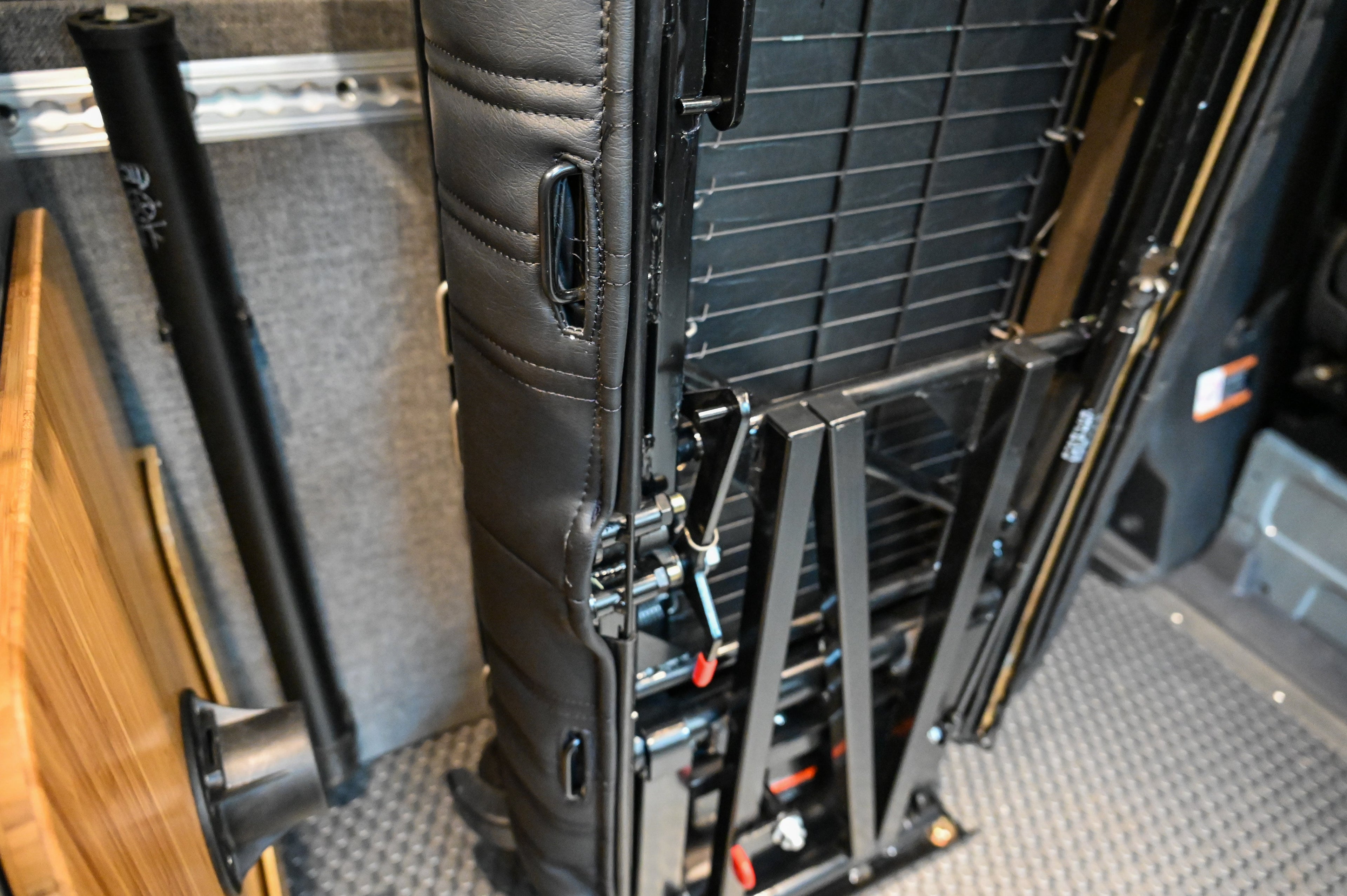 Alpine Van Works Hide N' Go Seat, a versatile folding seating solution with padded cushion, displayed in a vehicle interior.