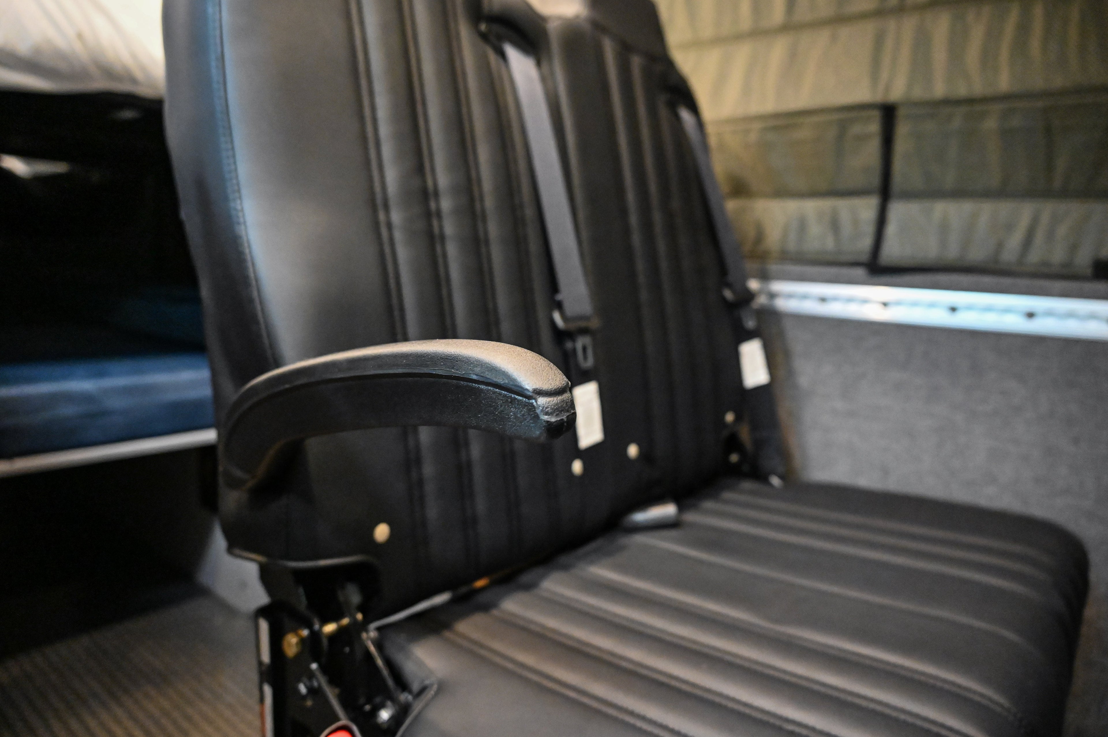 Alpine Van Works Hide N' Go Seat, a compact seating solution with versatile design, shown in a vehicle interior.