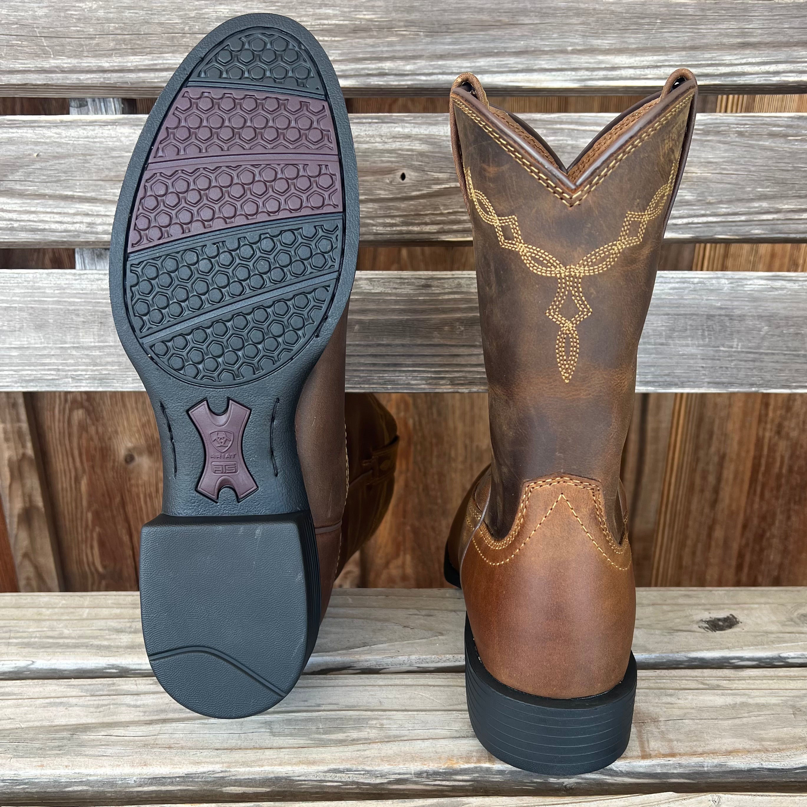 A pair of men's Heritage Roper Western boots by Ariat featuring brown leather and traditional Western stitching.