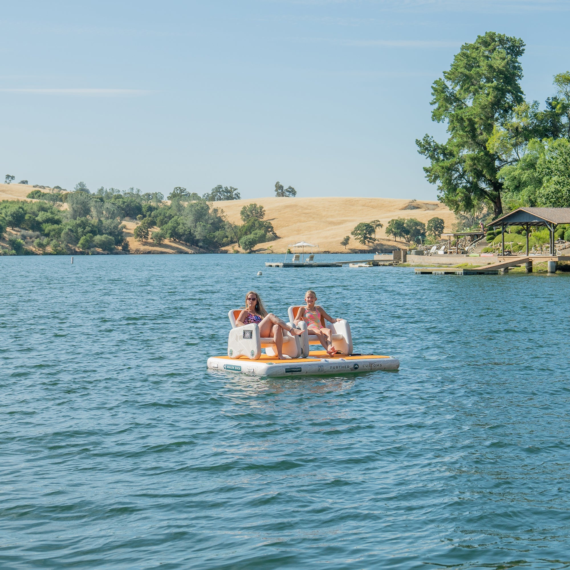 Inflatable Avalon Dock by Further Customs with floating deck, captain's chairs, and spacious platform for boating and water activities.