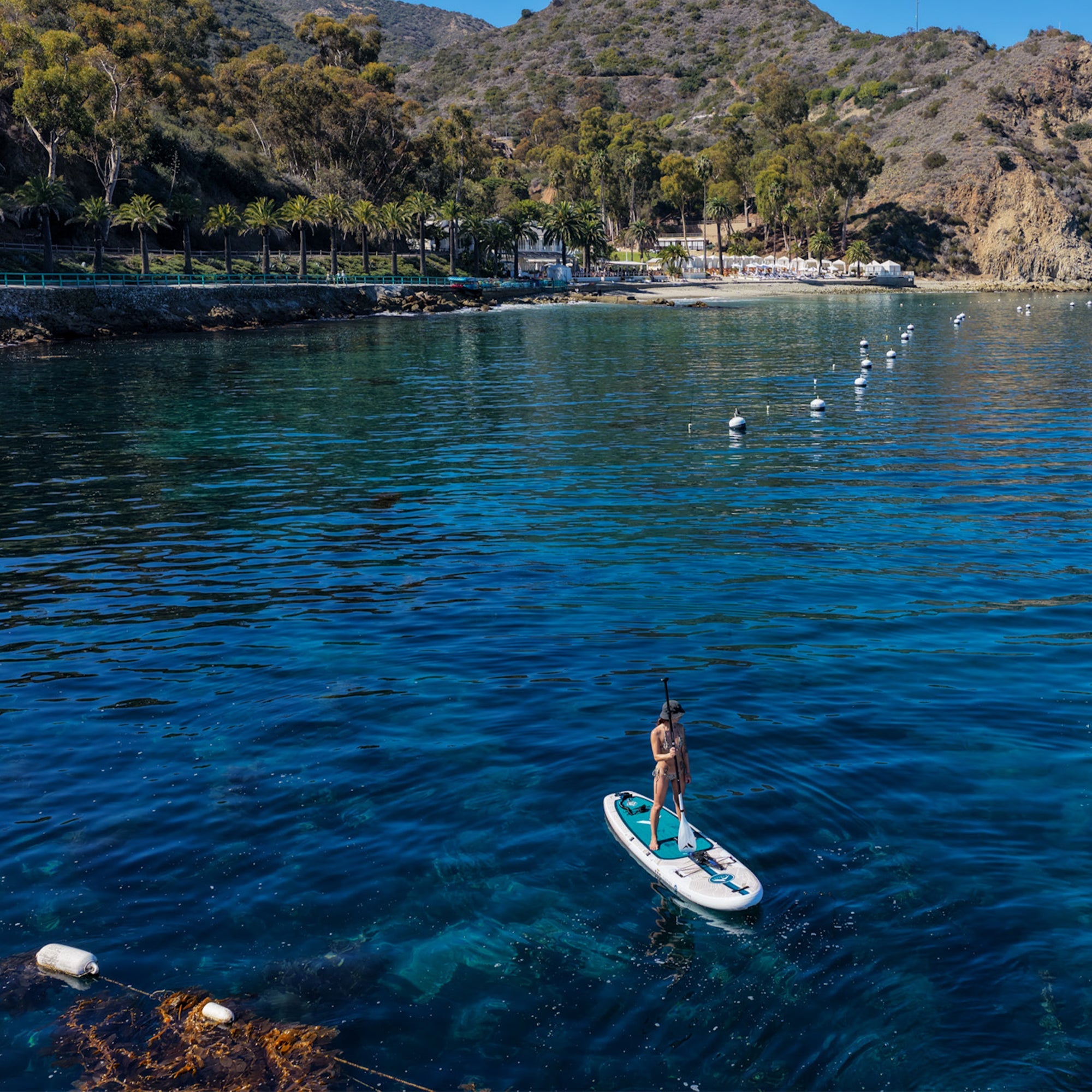 11'0 Further Customs Avalon Emerald inflatable paddleboard on a beach with clear water and scenic background.