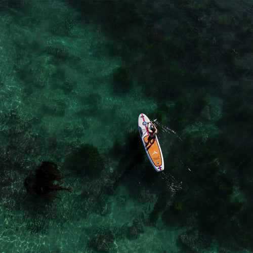 Further Customs 11'0 Avalon Mariner paddleboard on Brooks Laguna Beach, showcasing its sleek design and vibrant color.