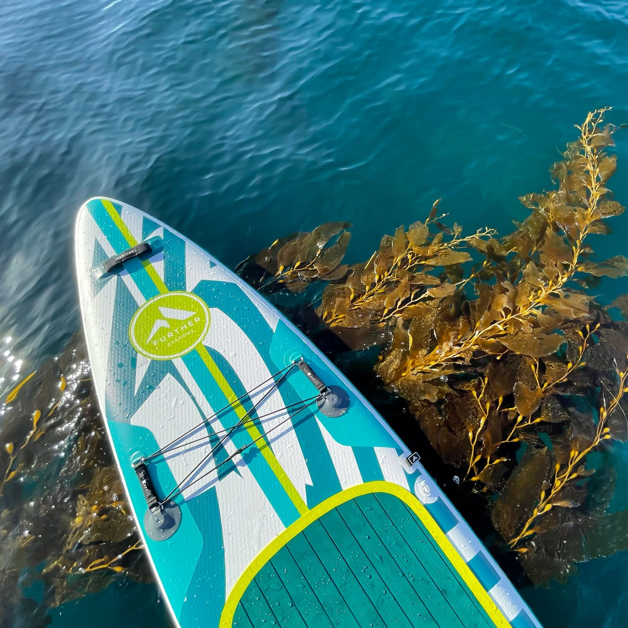 Further Customs 11'3" Podium turquoise inflatable paddleboard with a sleek design, suitable for stand-up paddleboarding in calm waters.