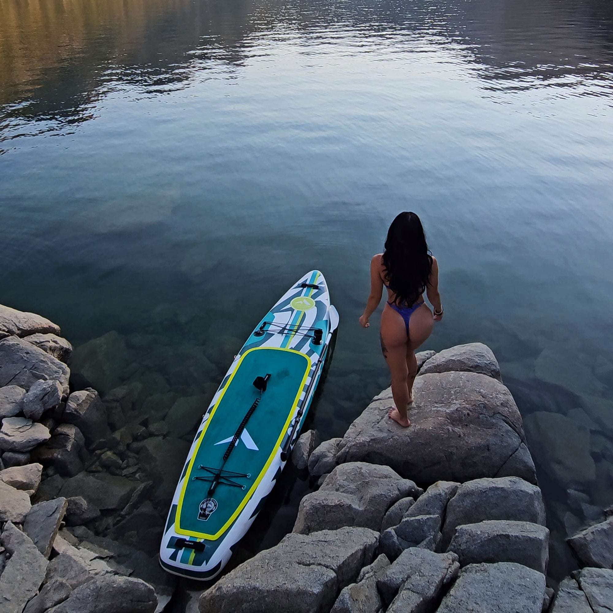 Further Customs 11'3 Podium turquoise inflatable paddleboard on lake, showing sleek design and ample deck space for paddleboarding.